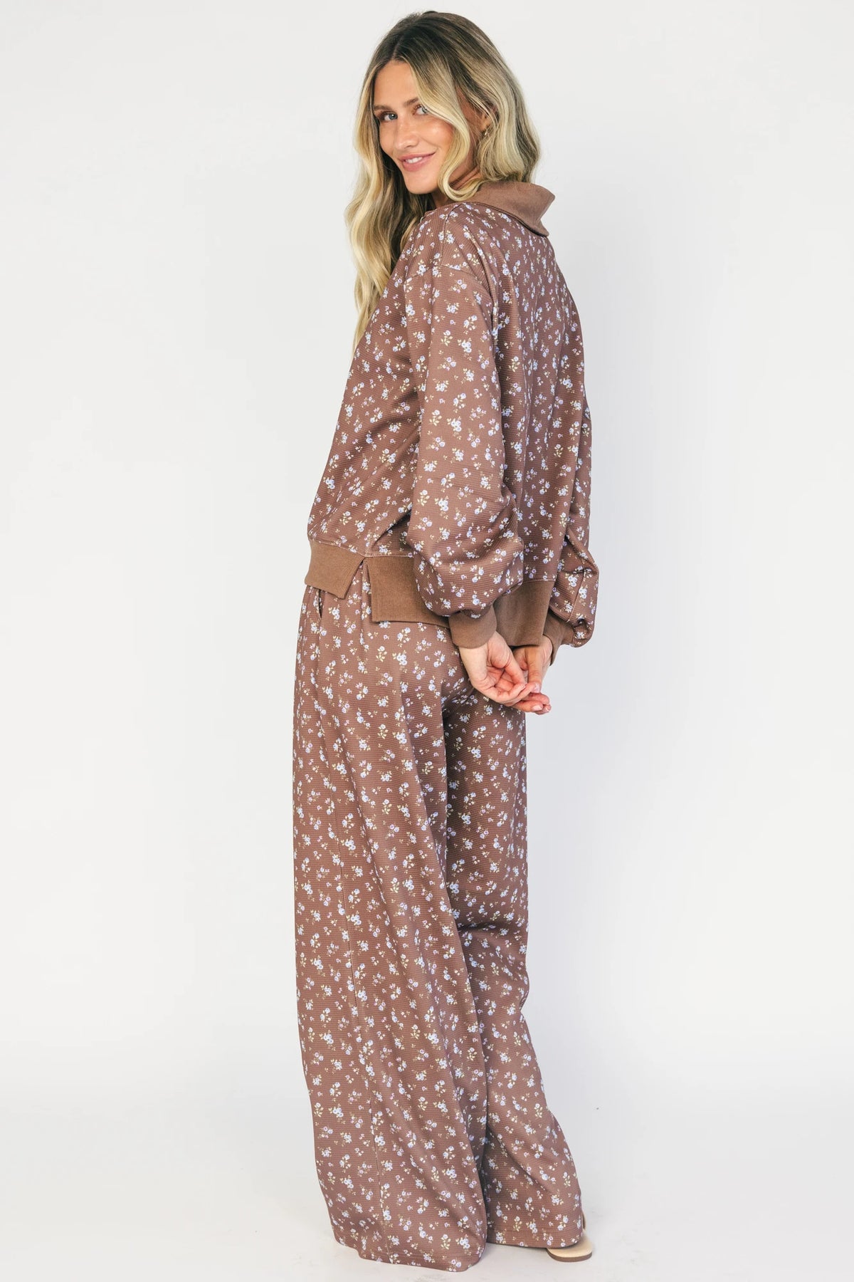 Model wearing the Diana Lounge Set in Brown Floral featuring a matching long-sleeve half-zip top and wide-leg pants.