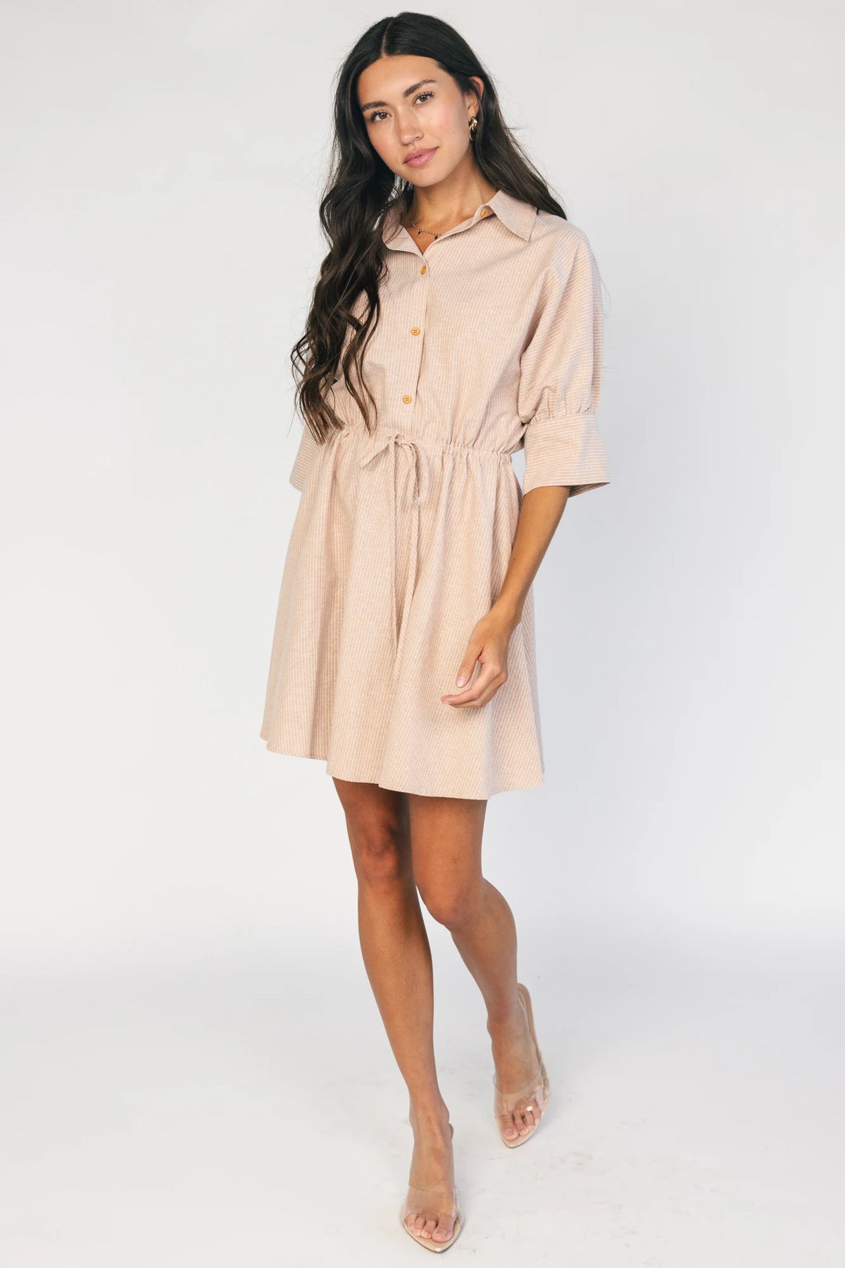 Model wearing the Beekman Short Dress in Natural Stripe featuring a collared neckline, functional button-front closure, elbow-length sleeves with wide cuffs, and a removable waist tie.