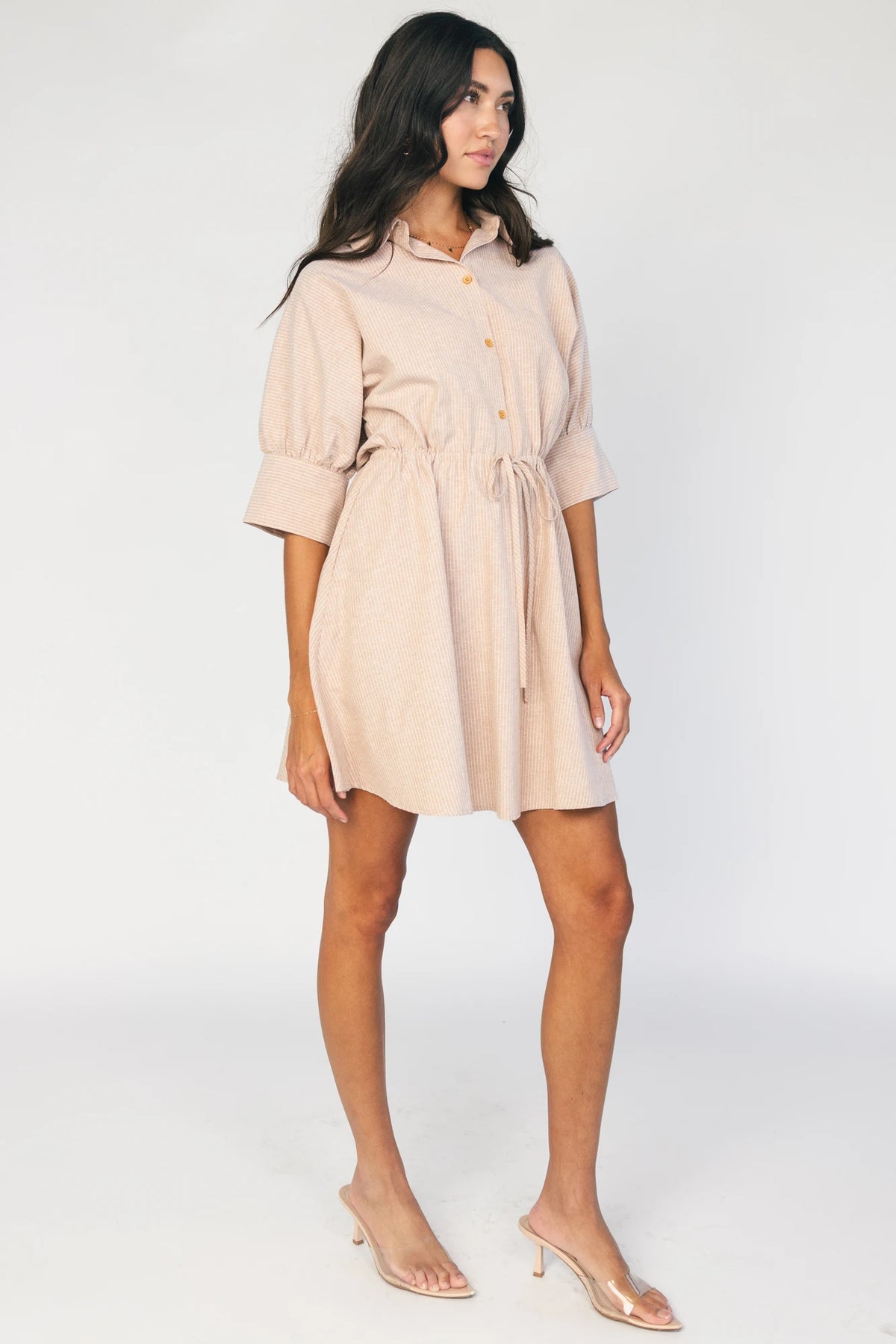 Model wearing the Beekman Short Dress in Natural Stripe featuring a collared neckline, functional button-front closure, elbow-length sleeves with wide cuffs, and a removable waist tie.