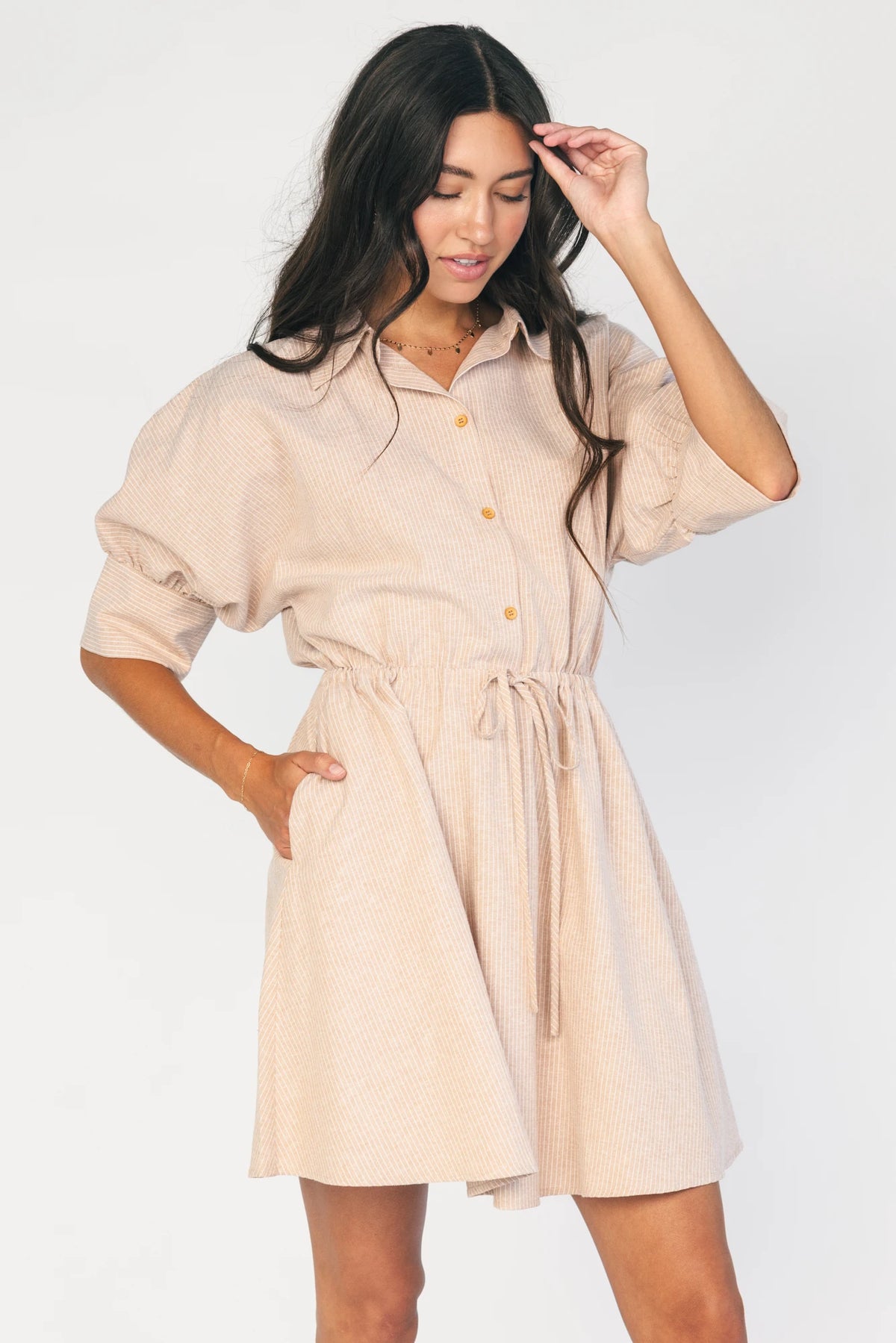 Model wearing the Beekman Short Dress in Natural Stripe featuring a collared neckline, functional button-front closure, elbow-length sleeves with wide cuffs, and a removable waist tie.