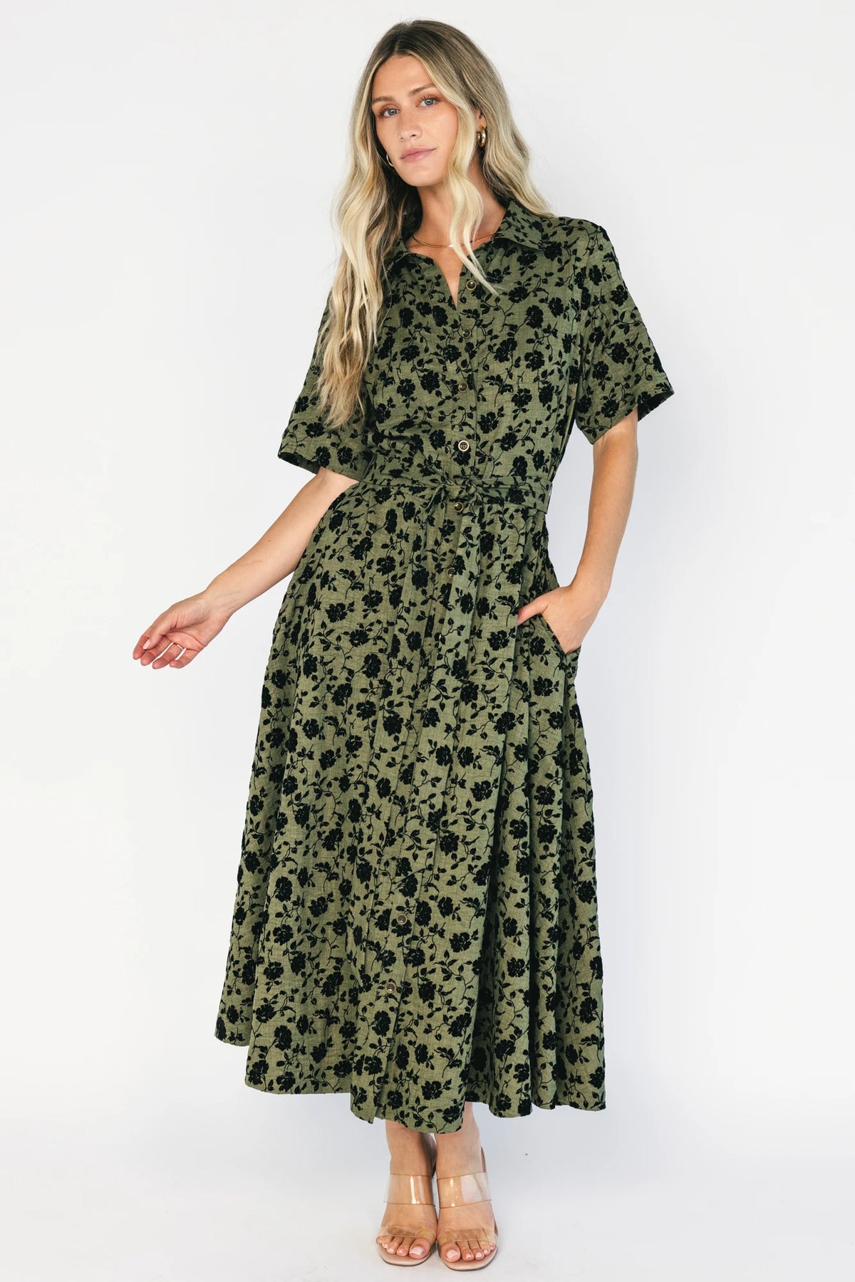 Deep olive floral midi shirt dress with a collared neckline, button-front closure, short sleeves, removable waist tie, side pockets, and fit-and-flare skirt.
