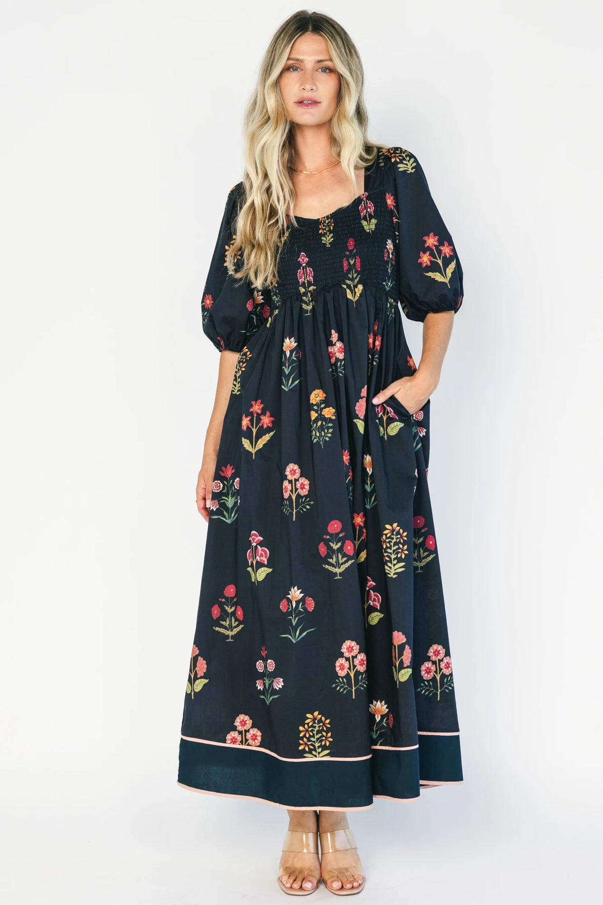 Navy floral maxi dress with a V-neckline, short puff sleeves, empire waist, fit-and-flare skirt, and contrast border hem.