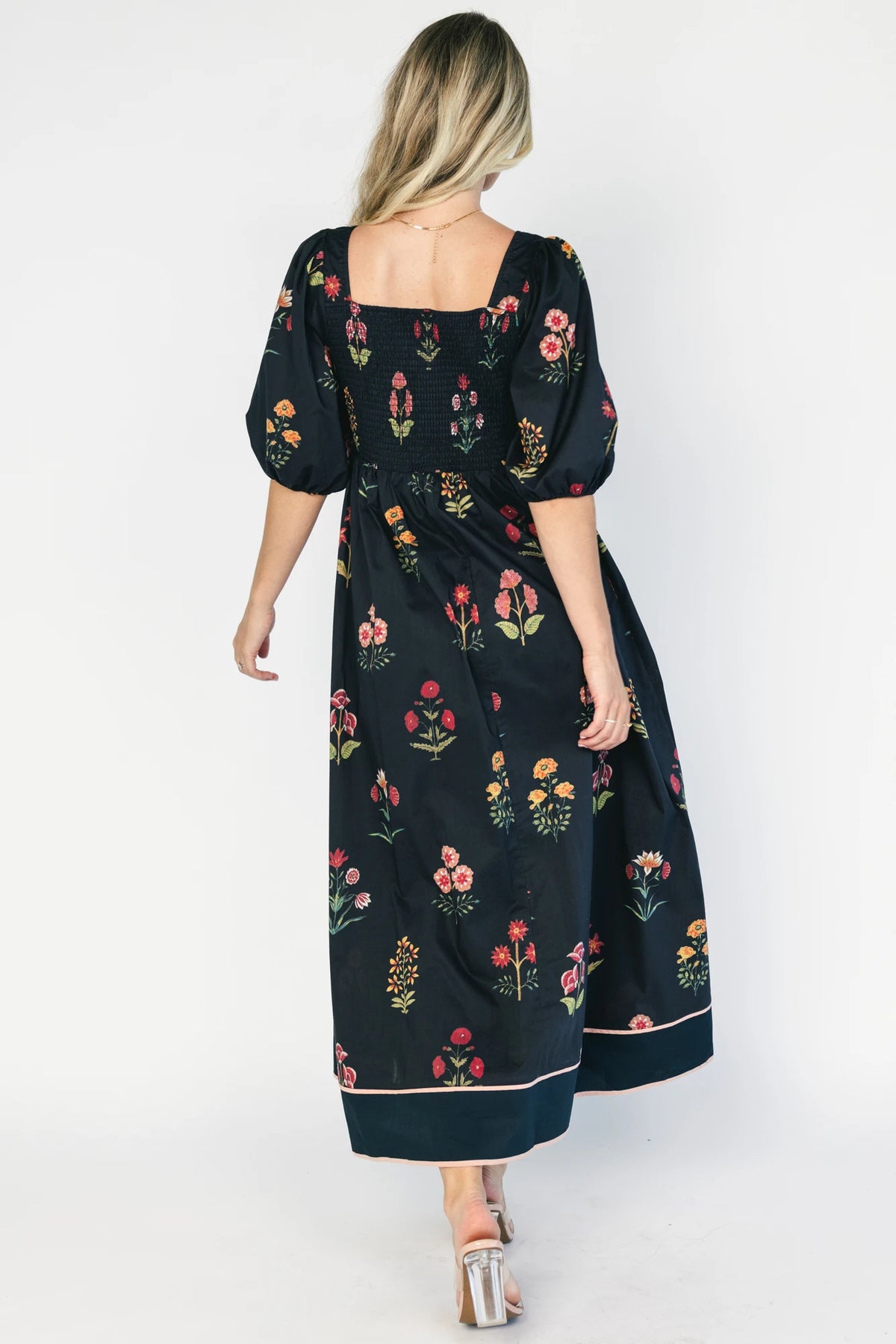 Navy floral maxi dress with a V-neckline, short puff sleeves, empire waist, fit-and-flare skirt, and contrast border hem.