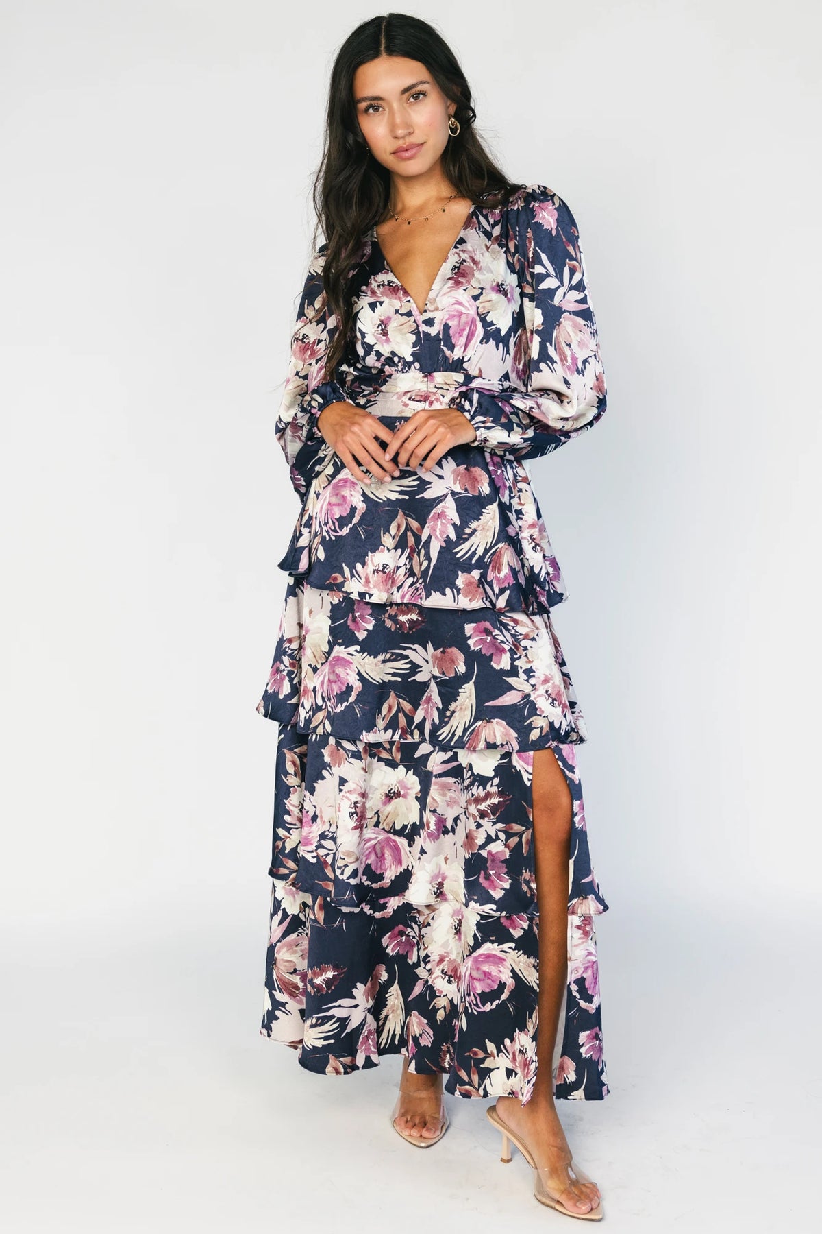 Model wearing the Montrouge Tiered Satin Maxi Dress in Navy + Lilac Floral featuring a V-neckline, short flutter sleeves, a smocked back, and a flowing tiered satin maxi skirt with a navy background and lilac floral print.