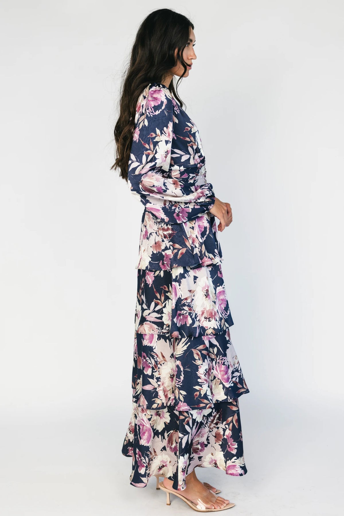 Model wearing the Montrouge Tiered Satin Maxi Dress in Navy + Lilac Floral featuring a V-neckline, short flutter sleeves, a smocked back, and a flowing tiered satin maxi skirt with a navy background and lilac floral print.