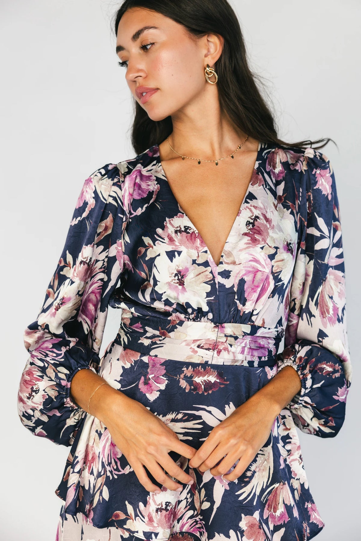 Model wearing the Montrouge Tiered Satin Maxi Dress in Navy + Lilac Floral featuring a V-neckline, short flutter sleeves, a smocked back, and a flowing tiered satin maxi skirt with a navy background and lilac floral print.