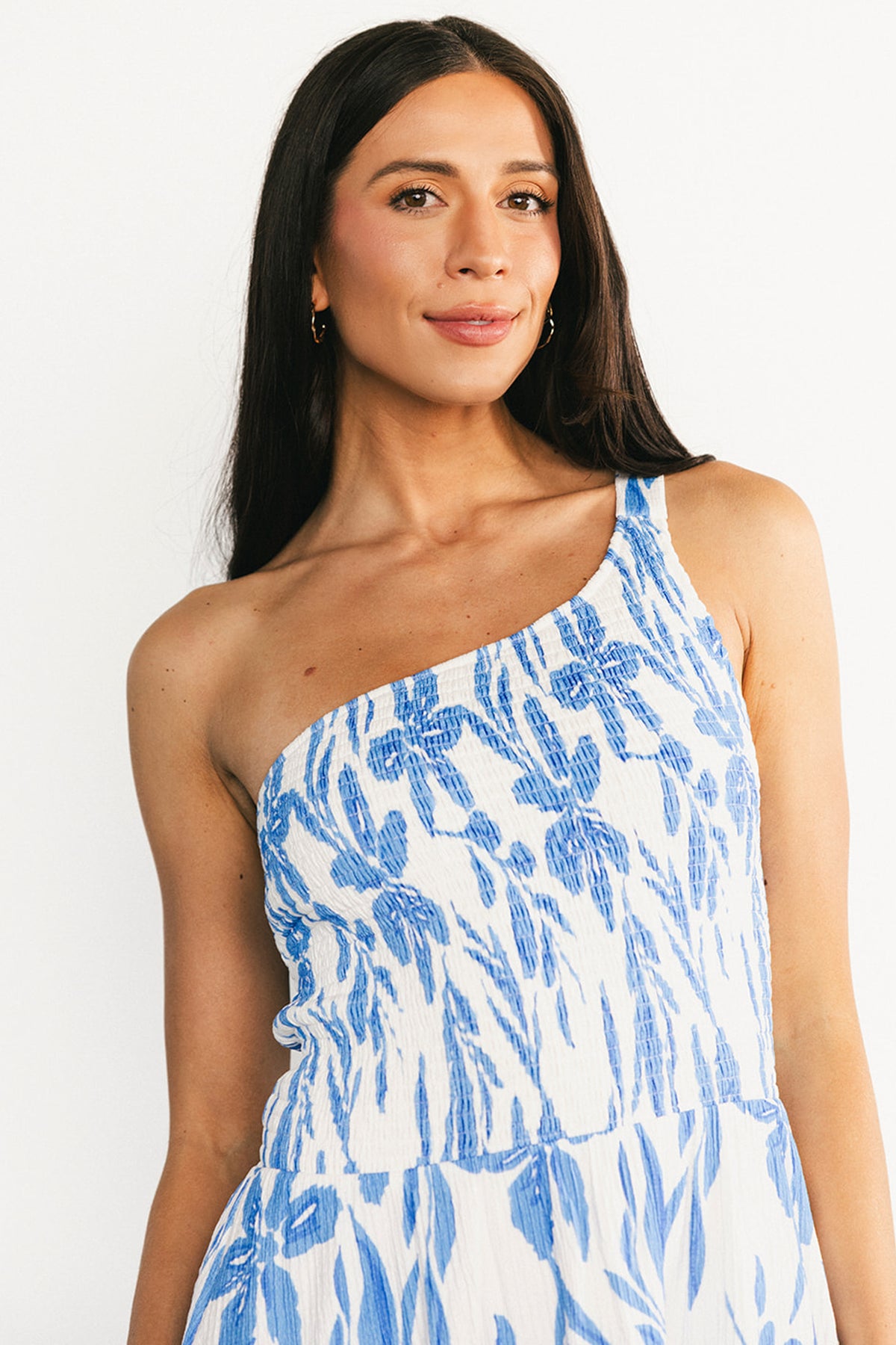 Close-up of the smocked bodice and one-shoulder strap on the white and blue Brisa dress, showing fabric texture and stretch.