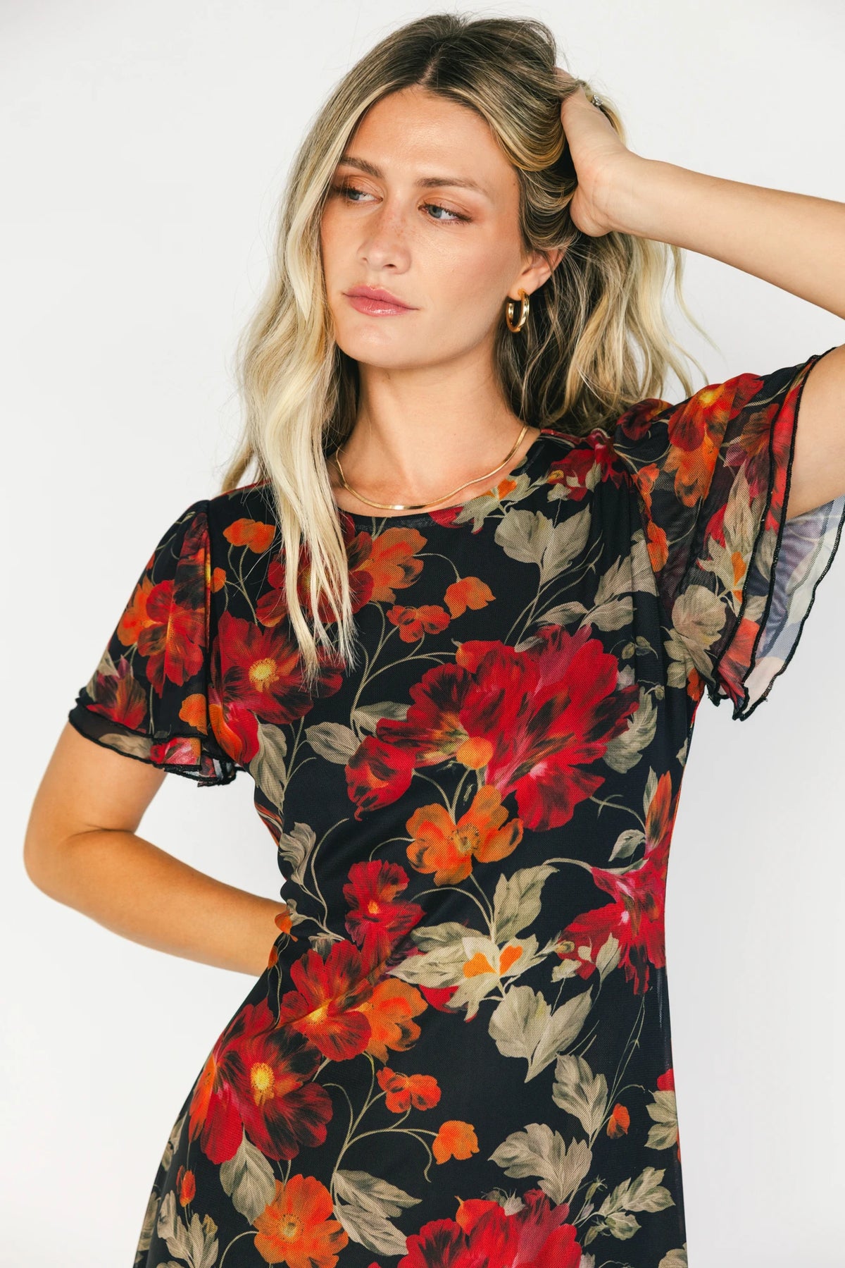 Black floral mesh maxi dress with a round neckline, layered flutter sleeves, bias-cut silhouette, and flowing full-length skirt.