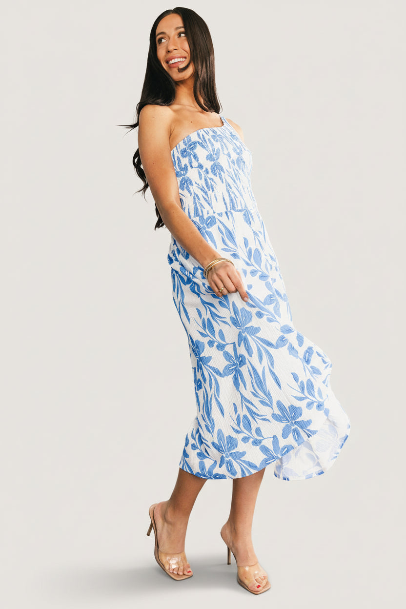 Studio full-length image of the Brisa midi dress in white and blue, highlighting the lined skirt, asymmetric neckline and overall elegant silhouette.