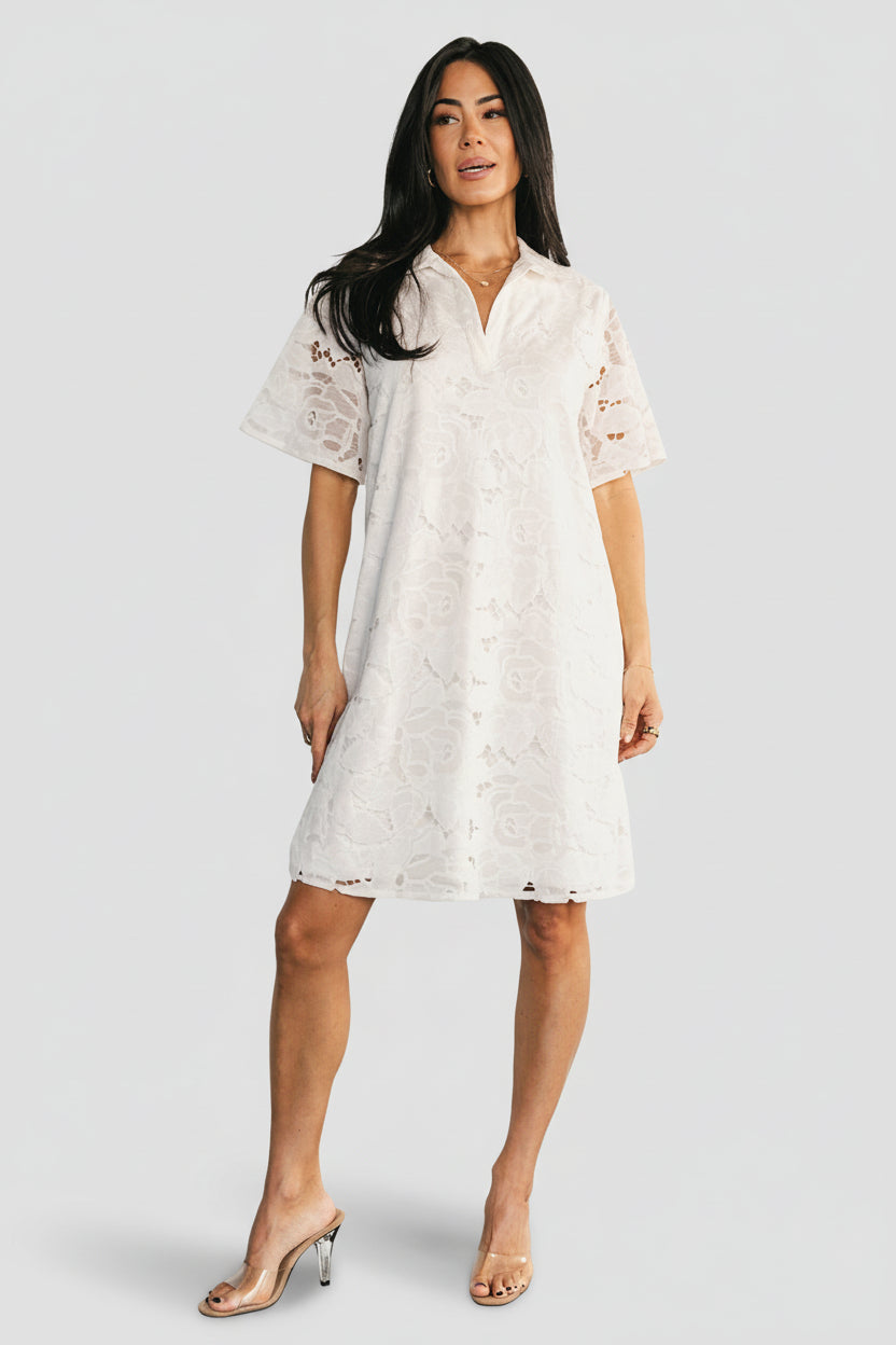 Model wearing Calida Lace Dress in off-white, front view showing V-neck, folded collar and short sheer sleeves on a shift silhouette.