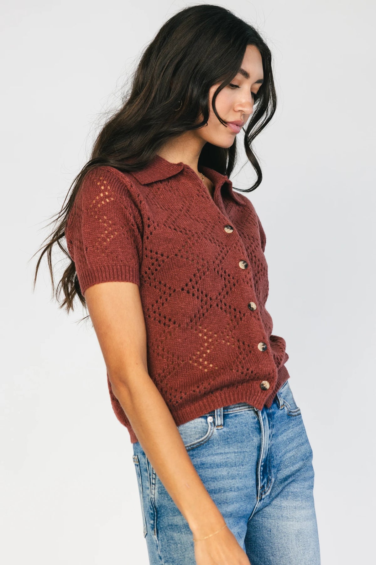 Model wearing a dark clay openwork knit cardigan with a V-neckline, short sleeves, five-button front closure, and a relaxed silhouette.