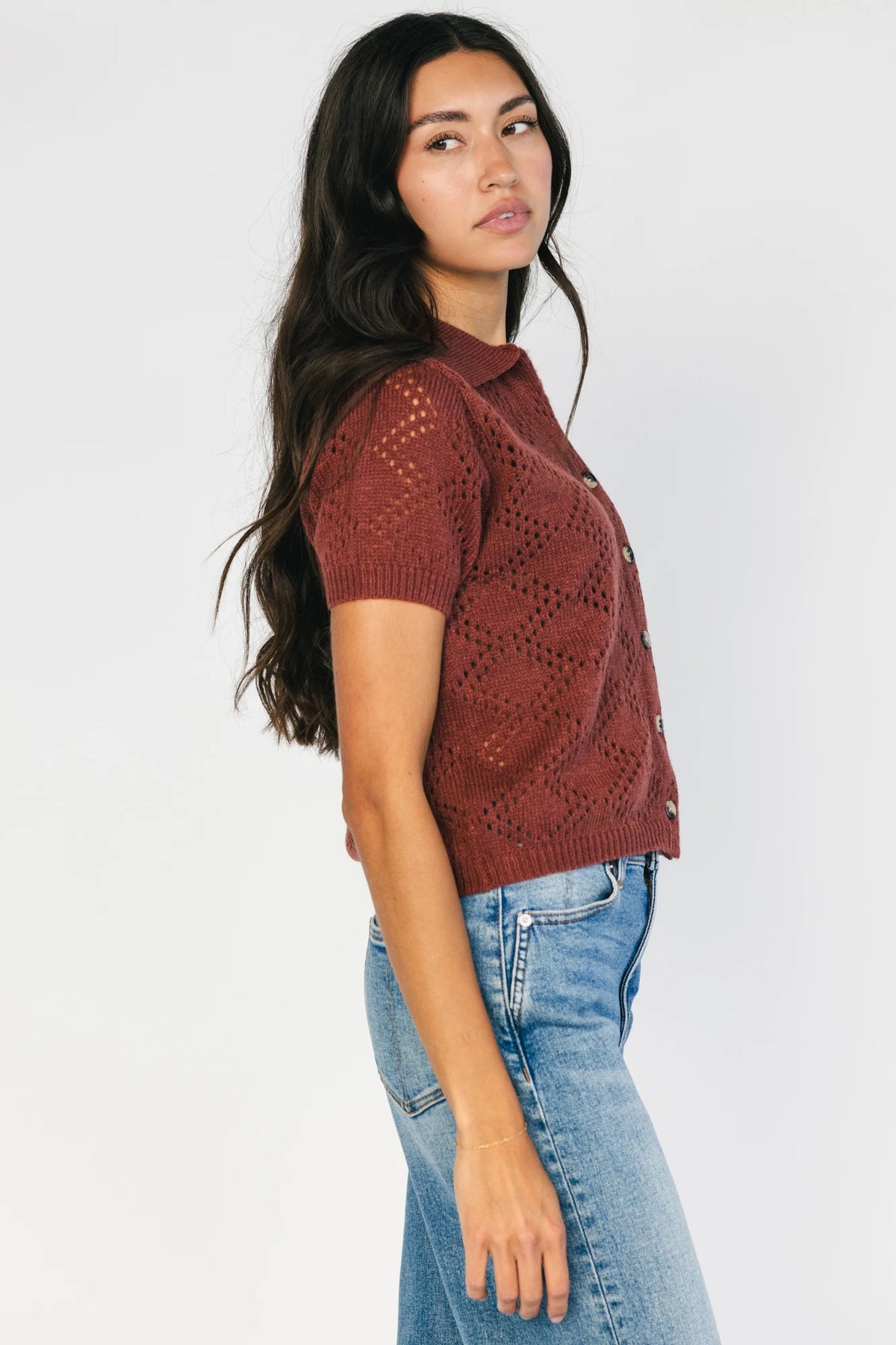 Model wearing a dark clay openwork knit cardigan with a V-neckline, short sleeves, five-button front closure, and a relaxed silhouette.