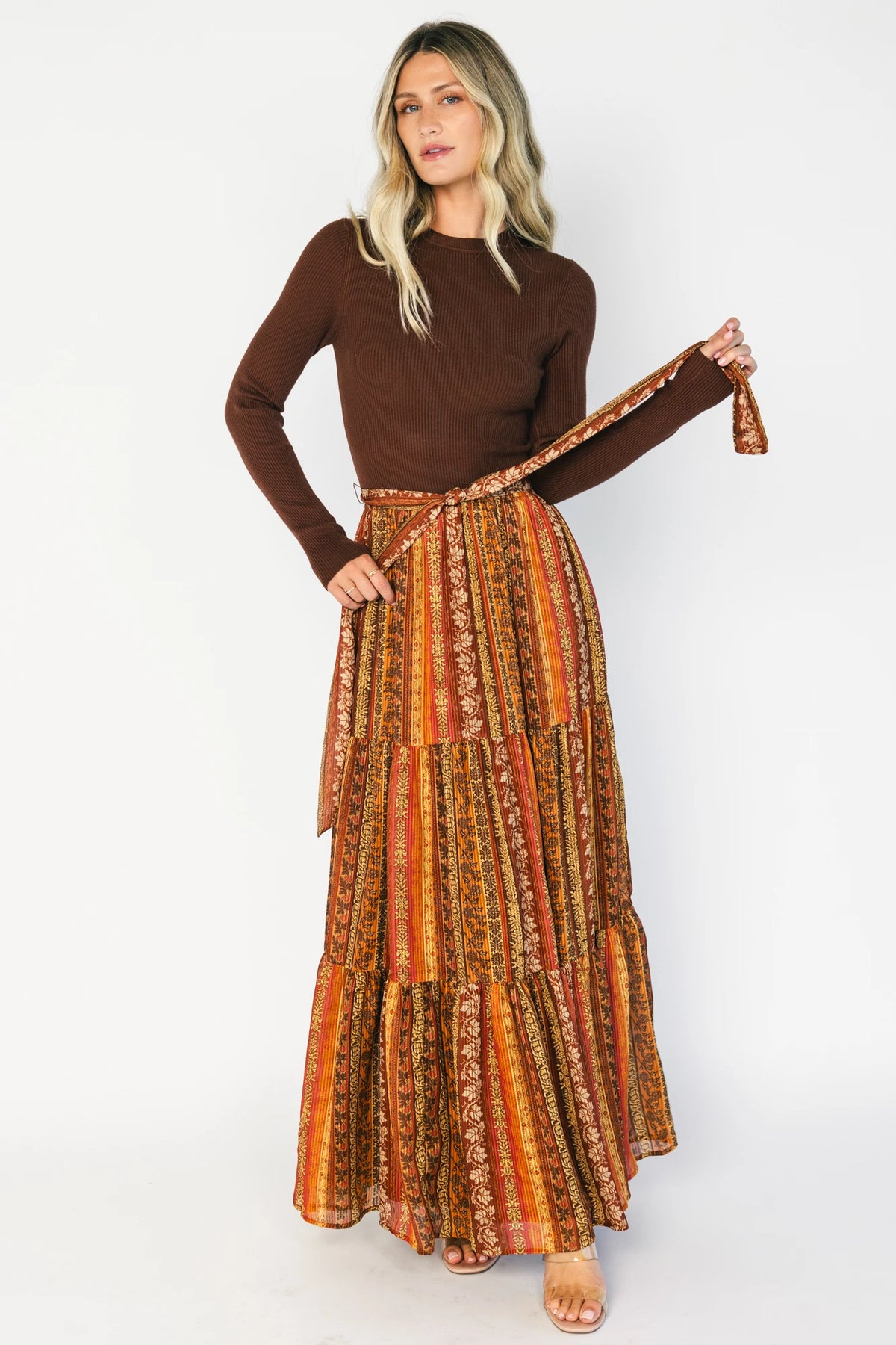Brown ribbed sweater maxi dress with long sleeves, a high round neckline, removable waist tie, and a flowing multicolor chiffon skirt.