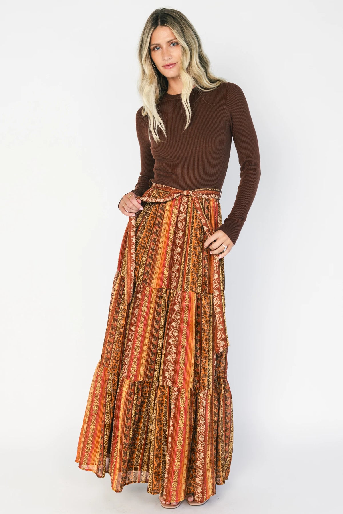 Brown ribbed sweater maxi dress with long sleeves, a high round neckline, removable waist tie, and a flowing multicolor chiffon skirt.