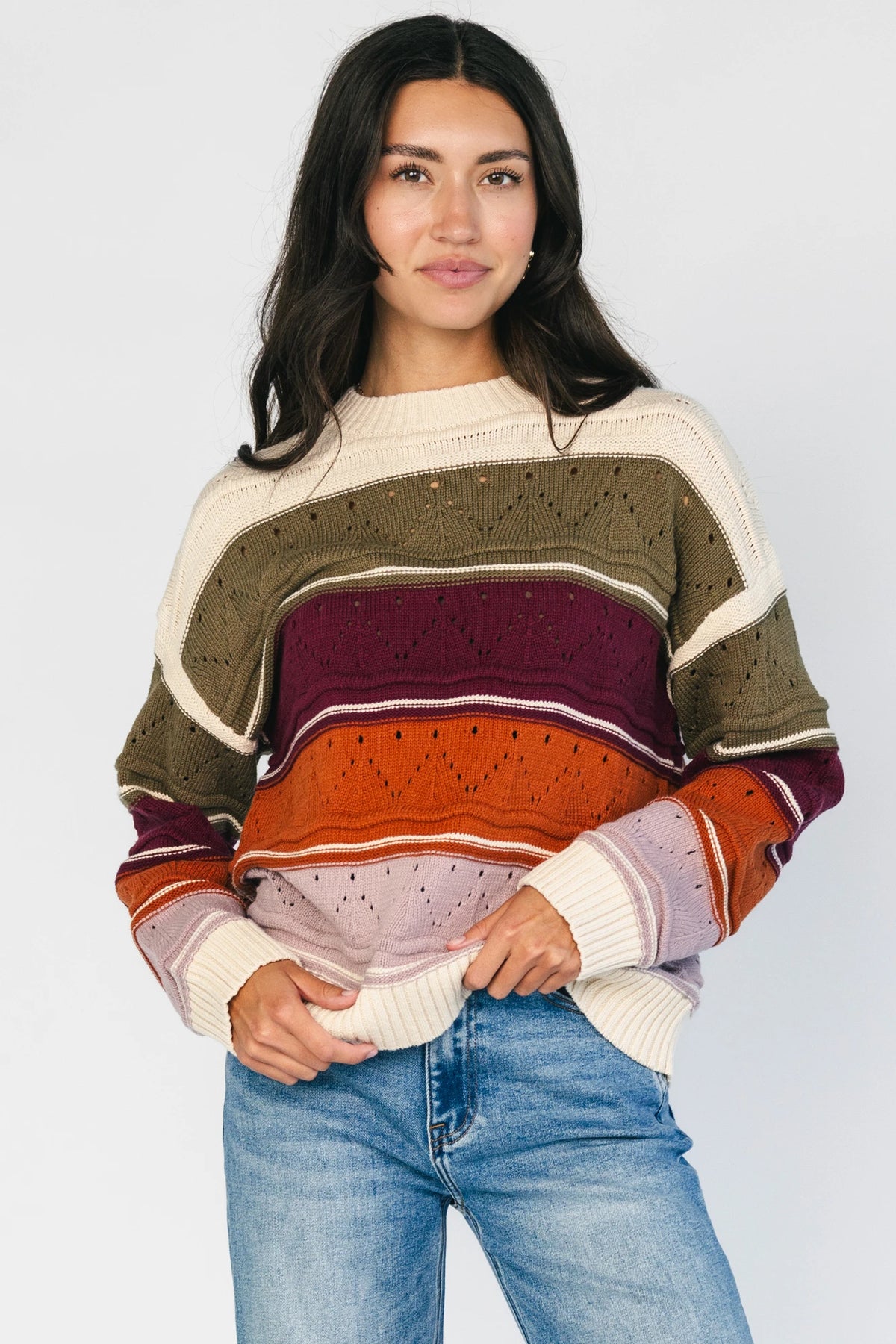 Ivory striped sweater with green, mulberry, rust, and purple horizontal stripes, a round neckline, dropped shoulders, long sleeves, and a relaxed fit.