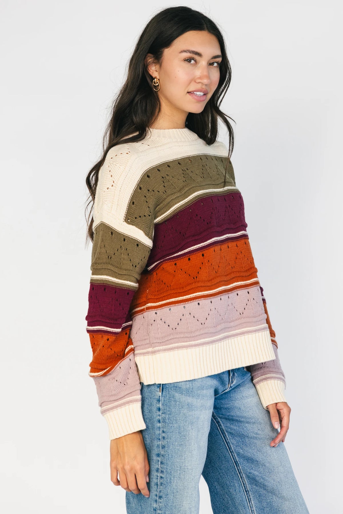 Ivory striped sweater with green, mulberry, rust, and purple horizontal stripes, a round neckline, dropped shoulders, long sleeves, and a relaxed fit.