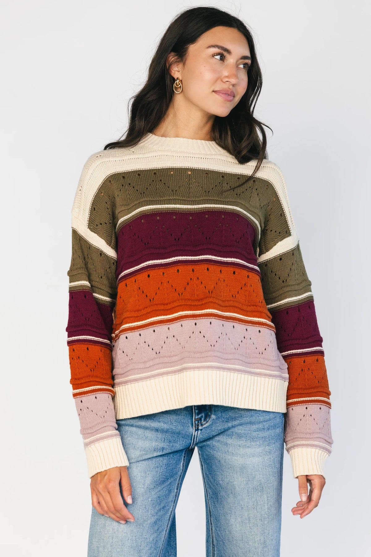 Ivory striped sweater with green, mulberry, rust, and purple horizontal stripes, a round neckline, dropped shoulders, long sleeves, and a relaxed fit.