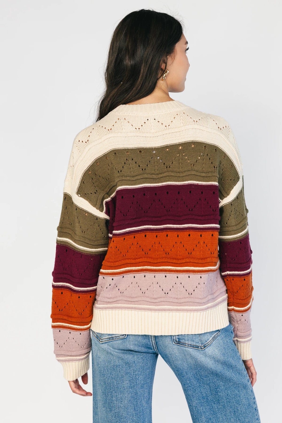 Ivory striped sweater with green, mulberry, rust, and purple horizontal stripes, a round neckline, dropped shoulders, long sleeves, and a relaxed fit.