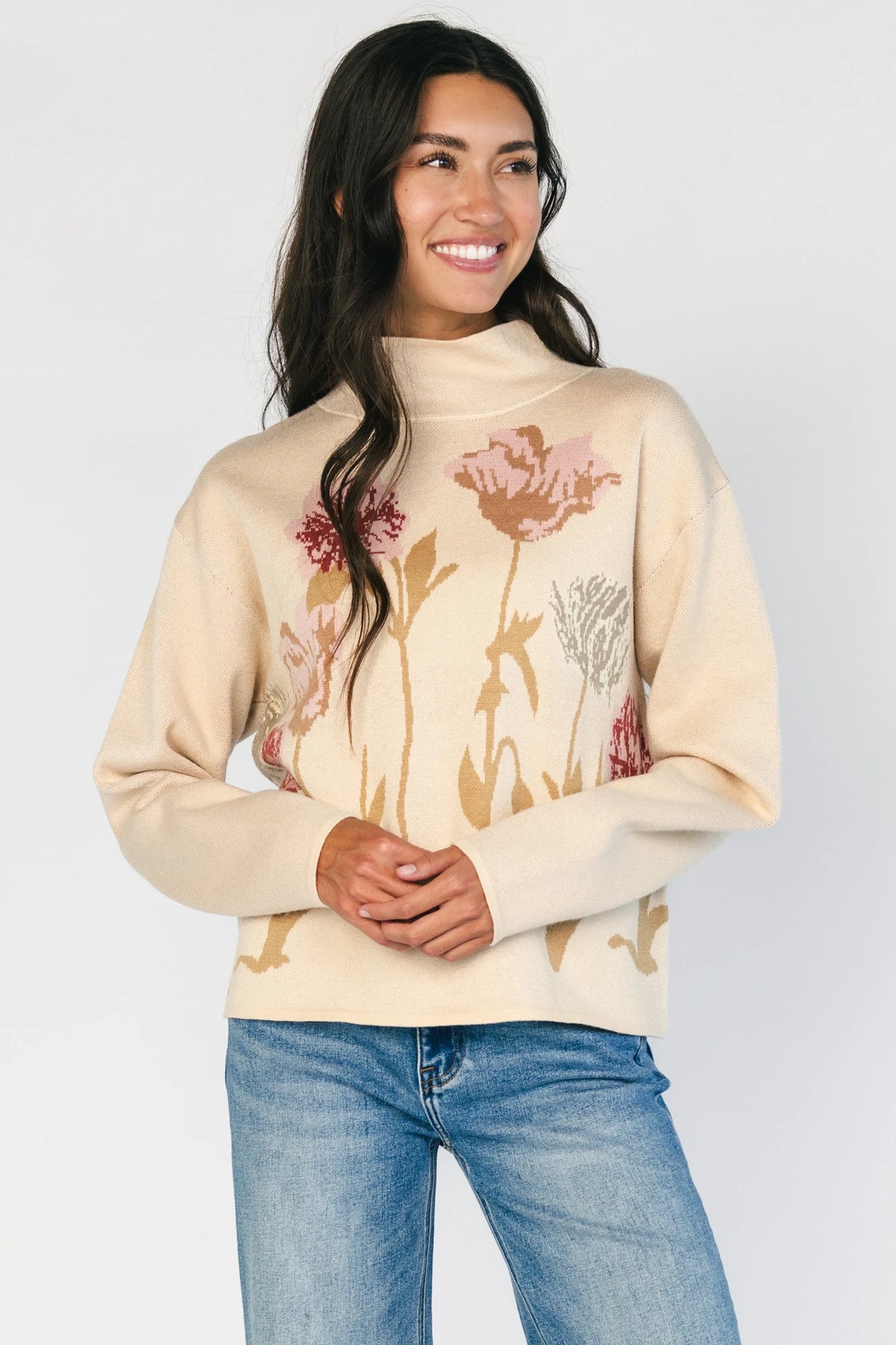 Natural knit sweater with a mock neckline, long sleeves, relaxed fit, and an embroidered floral motif at the neckline.