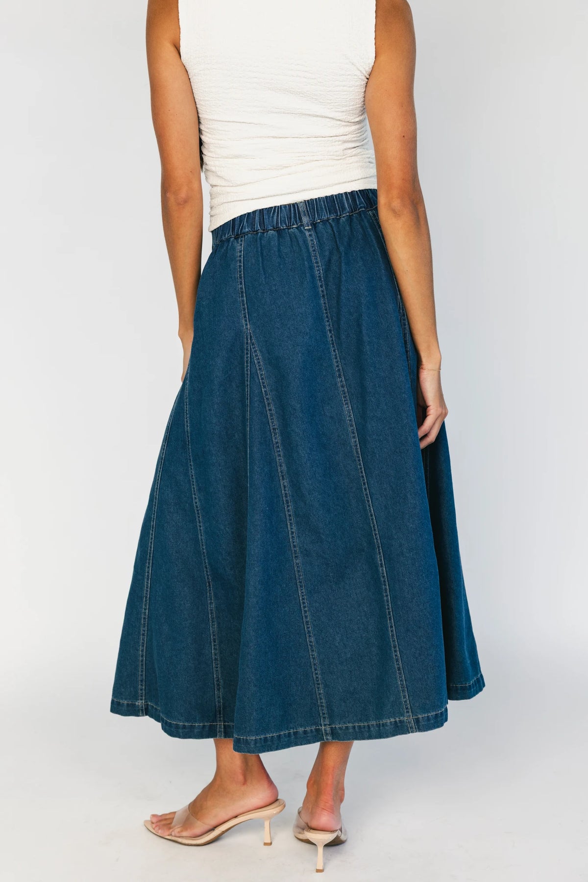 Model wearing the Cece Button-Down Denim Skirt in a dark wash featuring a button-front placket, elastic back waist, and a classic knee-length silhouette.
