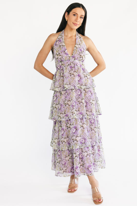 Model wearing lavender and olive floral halter maxi dress, front view showing plunging V-neckline and flowing chiffon skirt in soft light.
