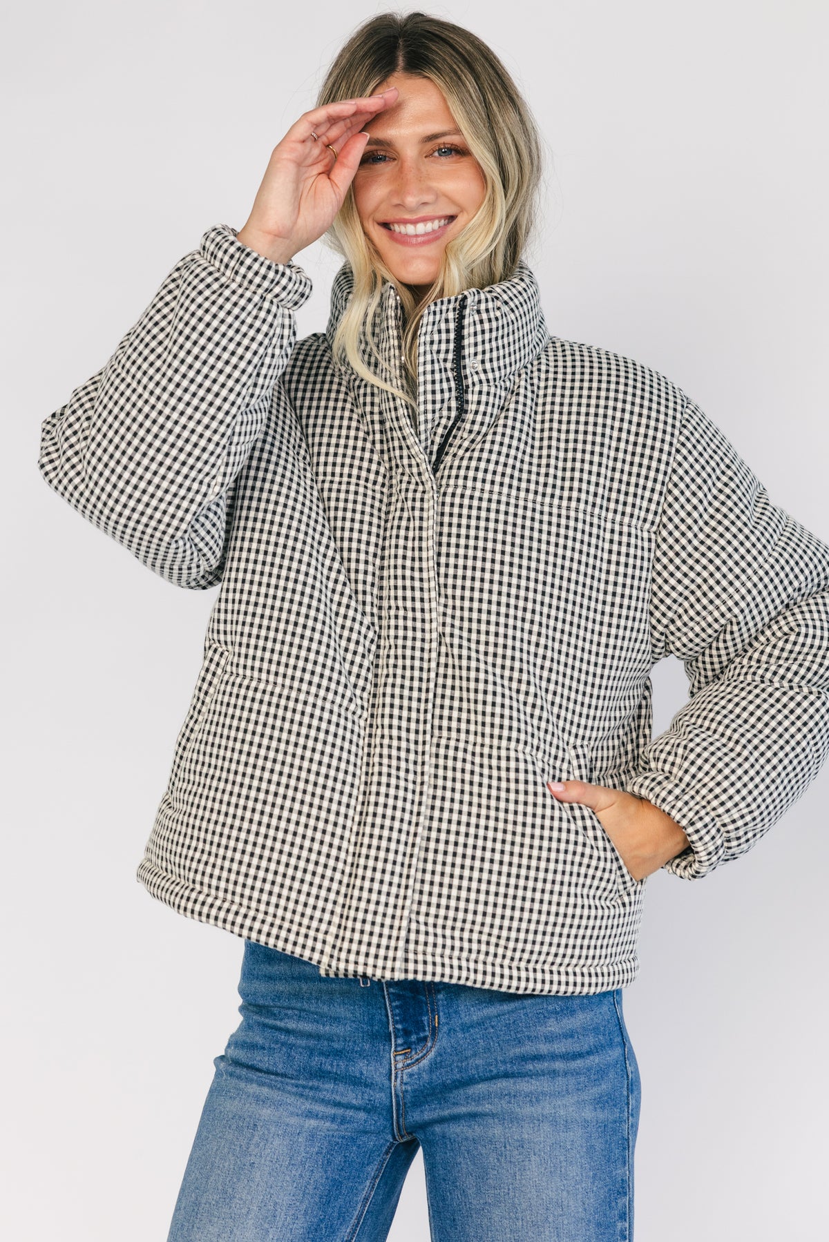 Model wearing the Vivienne Coat featuring a black and white gingham quilted puffer design with a high collar, front zipper and snap-button closure, long sleeves, and a relaxed silhouette.