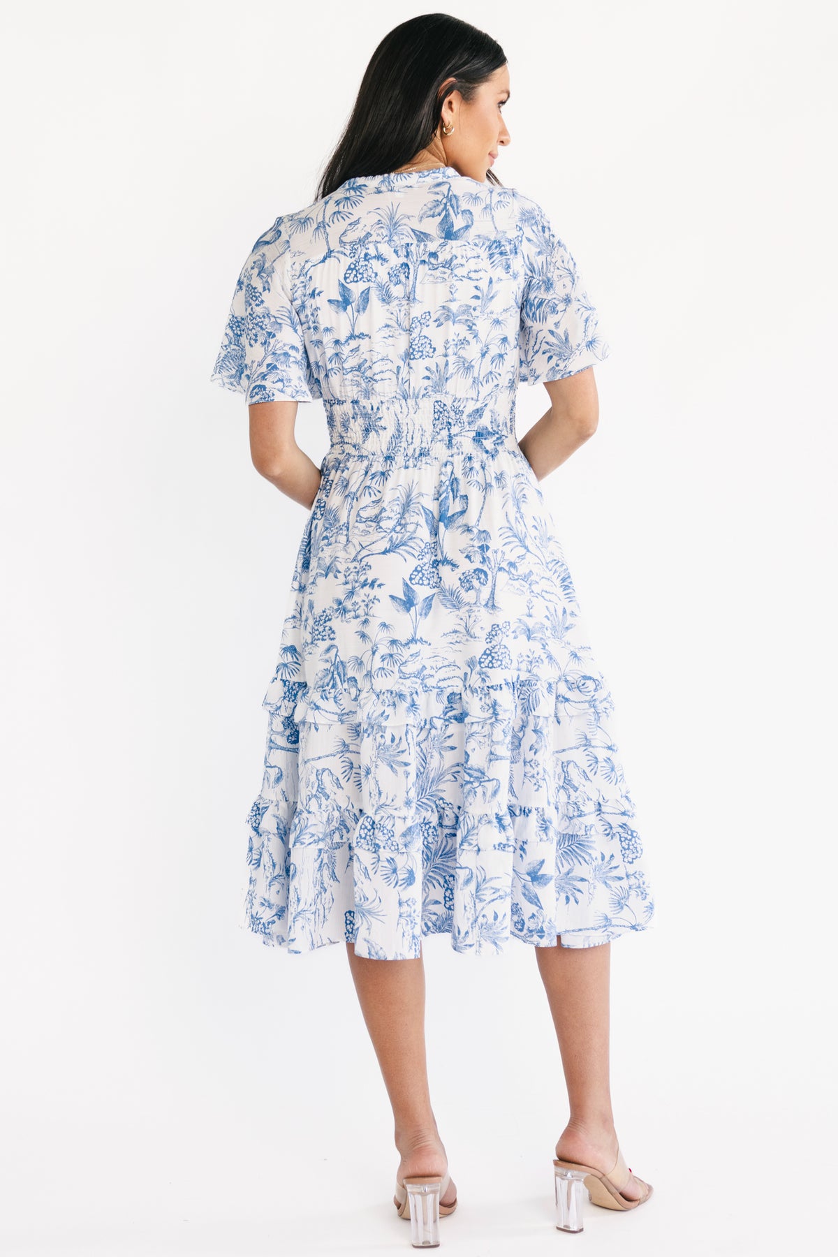Back view of Willow Boho Midi Dress with V-neckline detail, gathered yoke, and tiered ruffle skirt in white and blue tropical pattern.