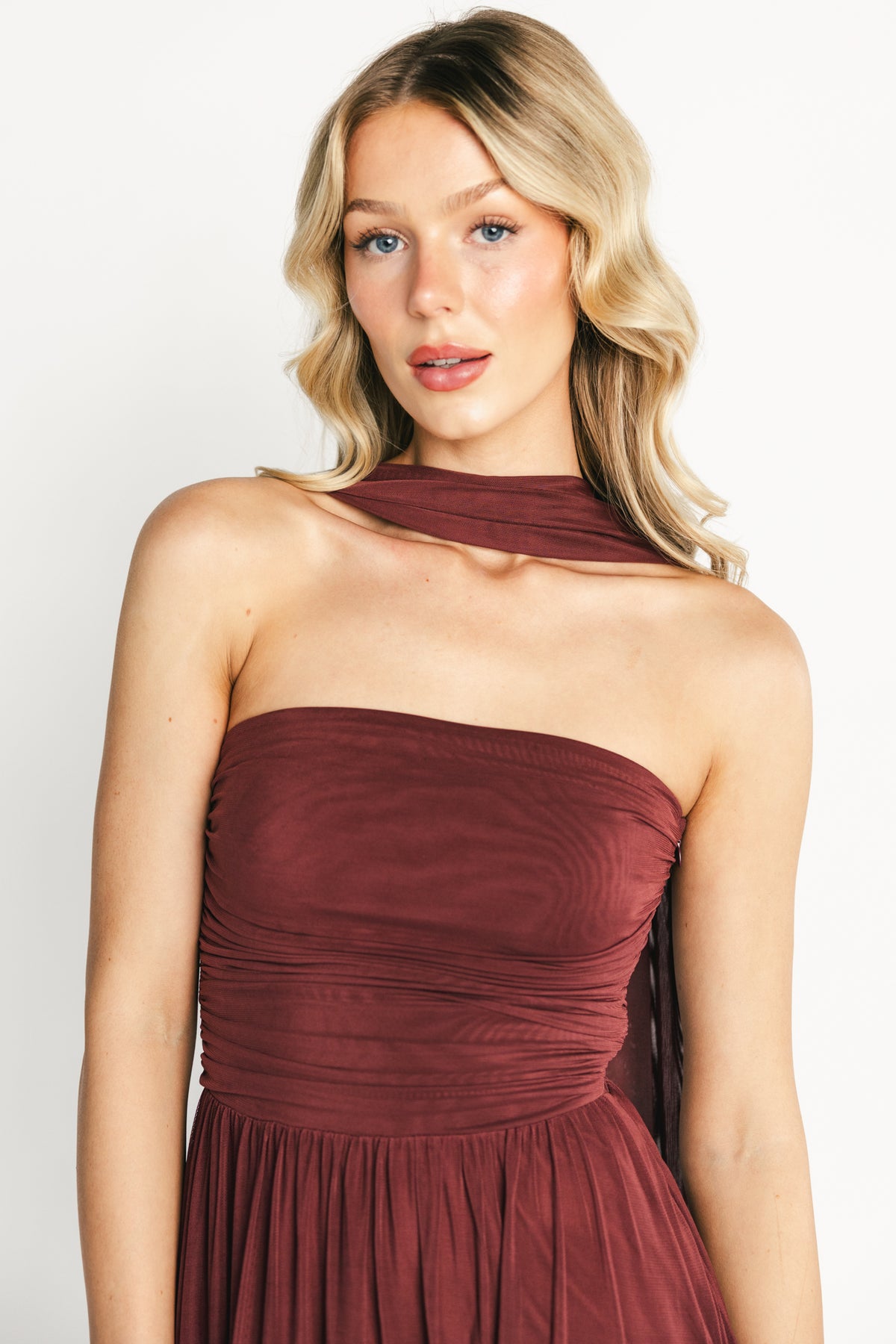 Side view of model in mahogany Elias strapless maxi dress showing fitted silhouette, elastic grip at bodice, and drape.