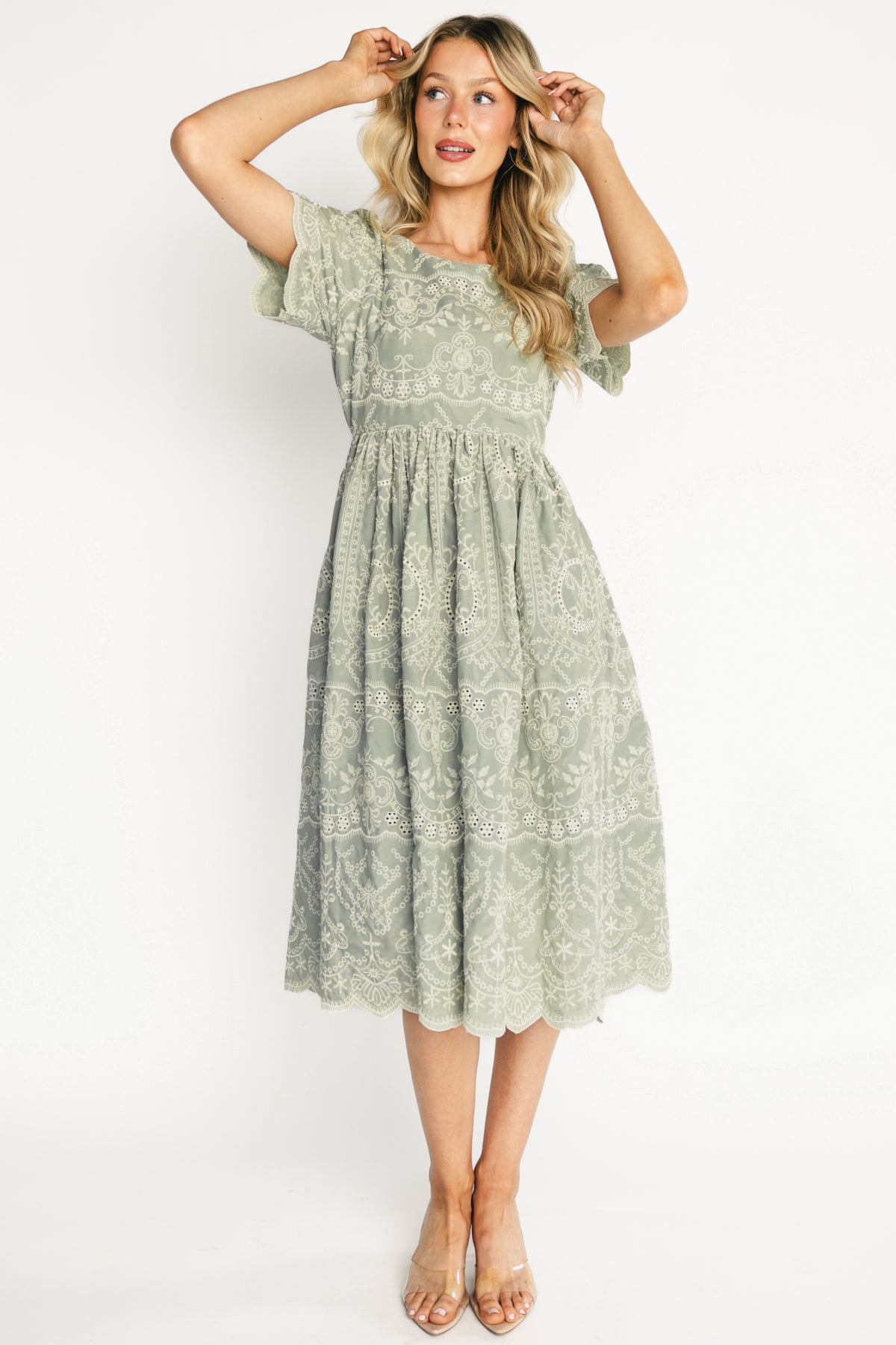 Front view of Margot Eyelet Midi Dress in sage green showing embroidered white eyelet, scalloped sleeves, and midi skirt hem.