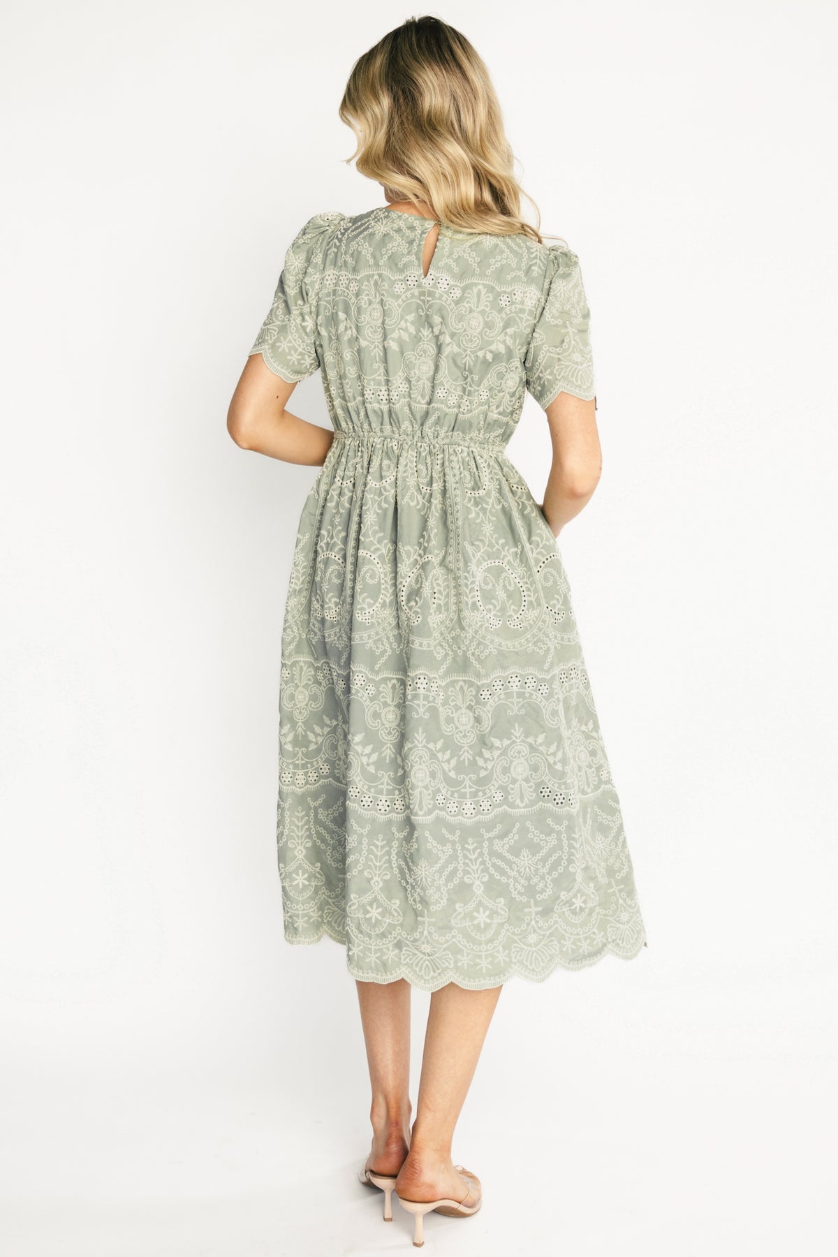 Detail shot of embroidered eyelet fabric and lined skirt on the Margot Eyelet Midi Dress in sage green, showing texture.