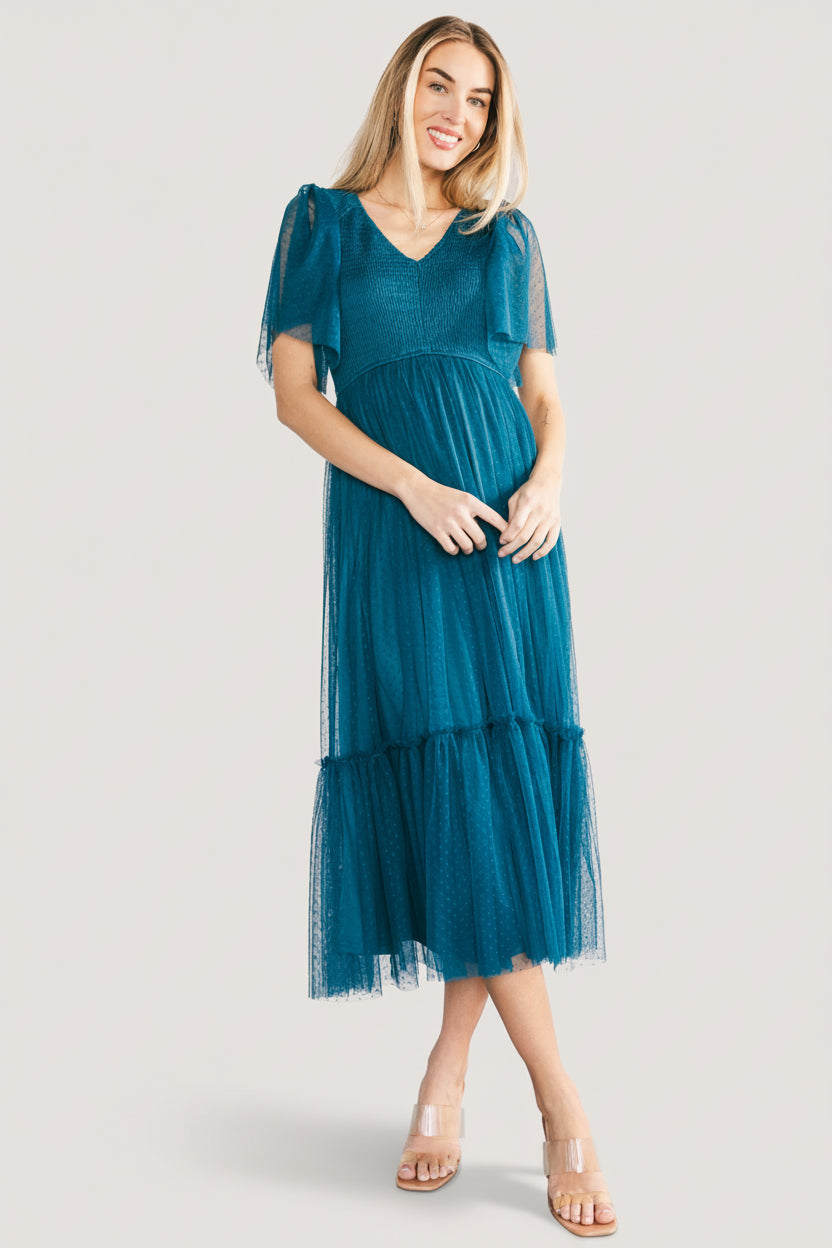Styled shot of the teal midi dress on model in a photographic setting, illustrating fit at waist, skirt movement, and lining coverage.