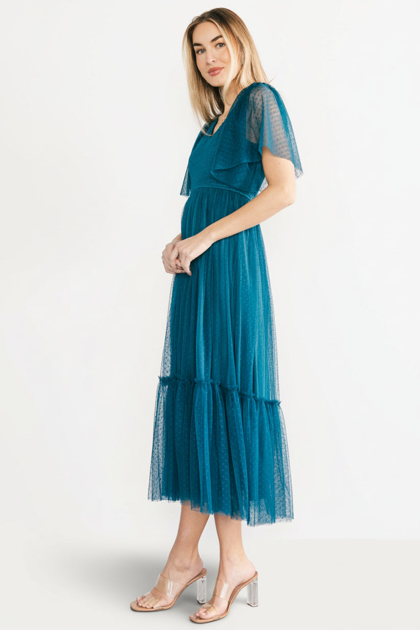 Side profile of the teal Martha dress highlighting angled front waistline, short flirty tulle sleeves, and the midi length silhouette.