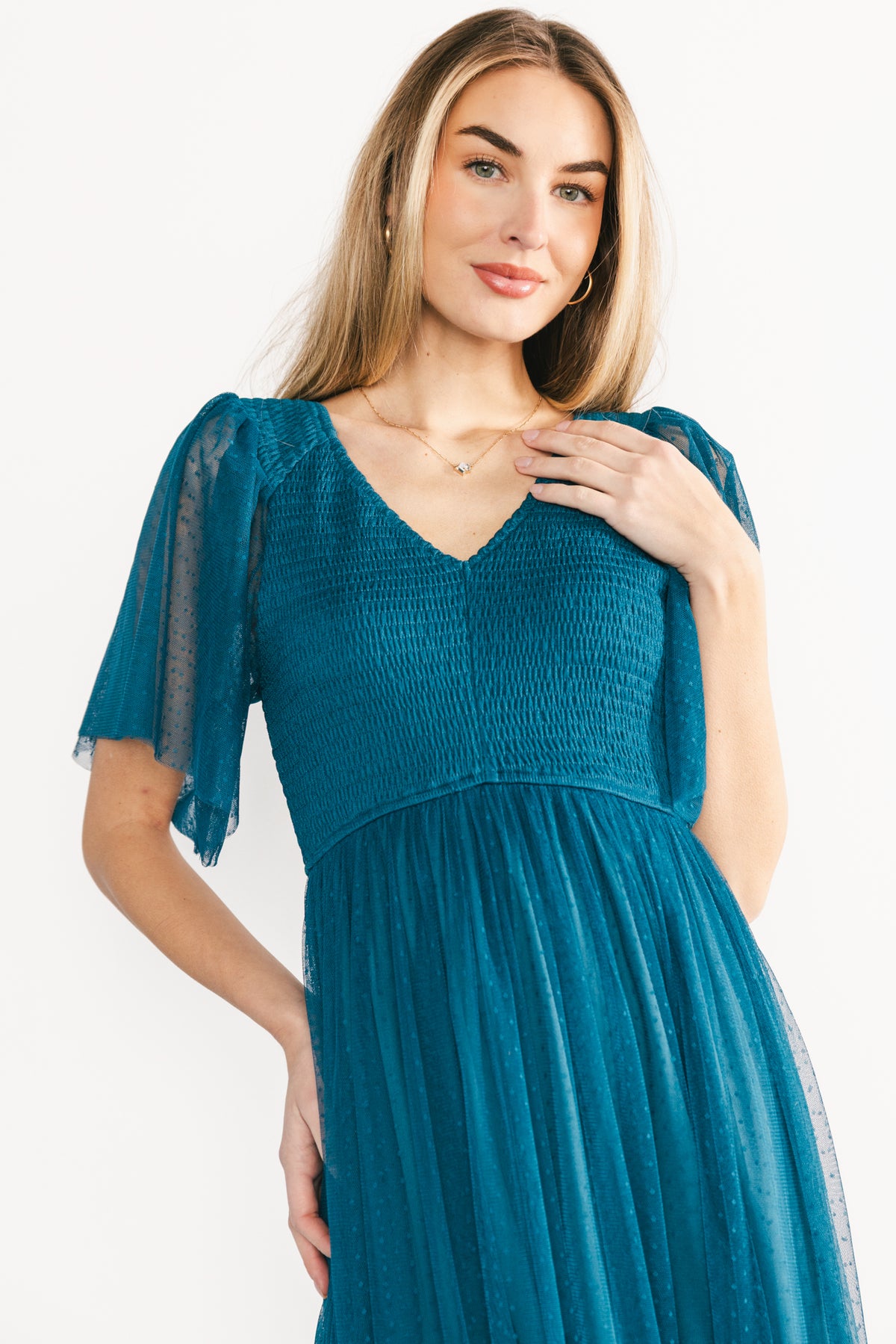 Close-up of the teal dress bodice featuring elastic smocking, Swiss-dot tulle overlay, and delicate V-neck detailing with slight gather.