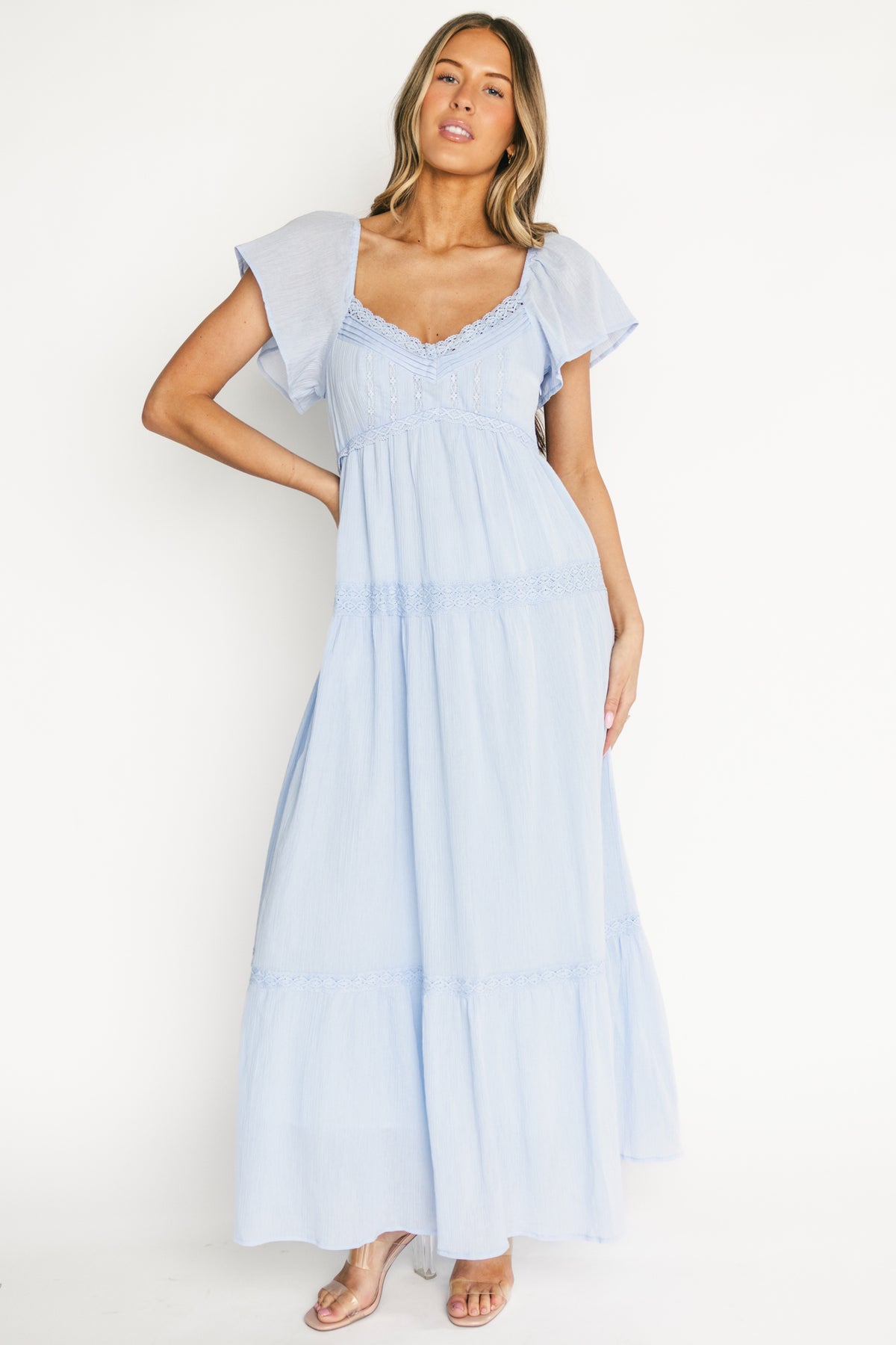 Side view showing left-side zipper and empire waistline flowing into a tiered maxi skirt with lace-trim accents.