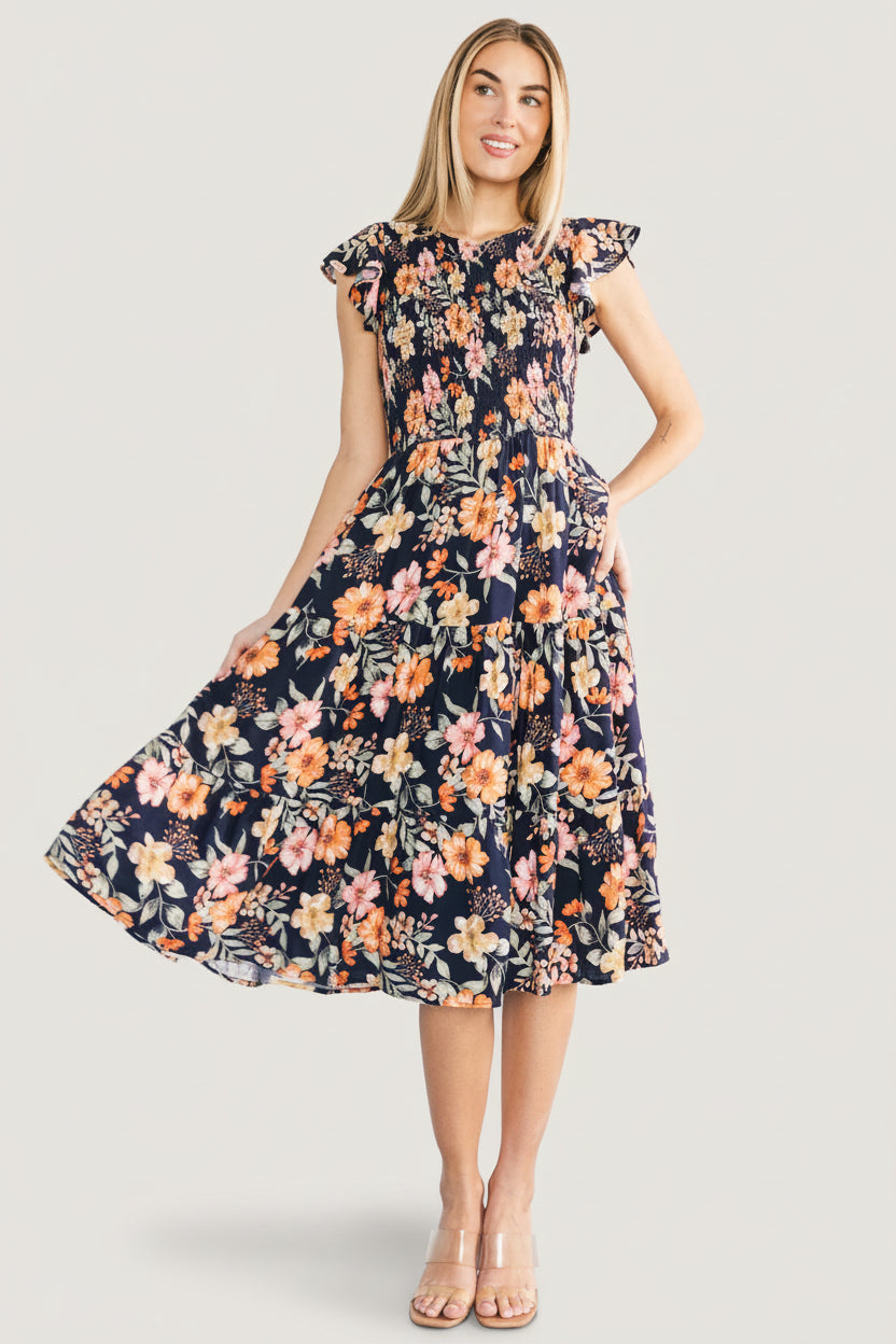 Model wearing midnight floral Loretta midi dress in a three-quarter profile, highlighting flowy three-tier skirt and natural movement.