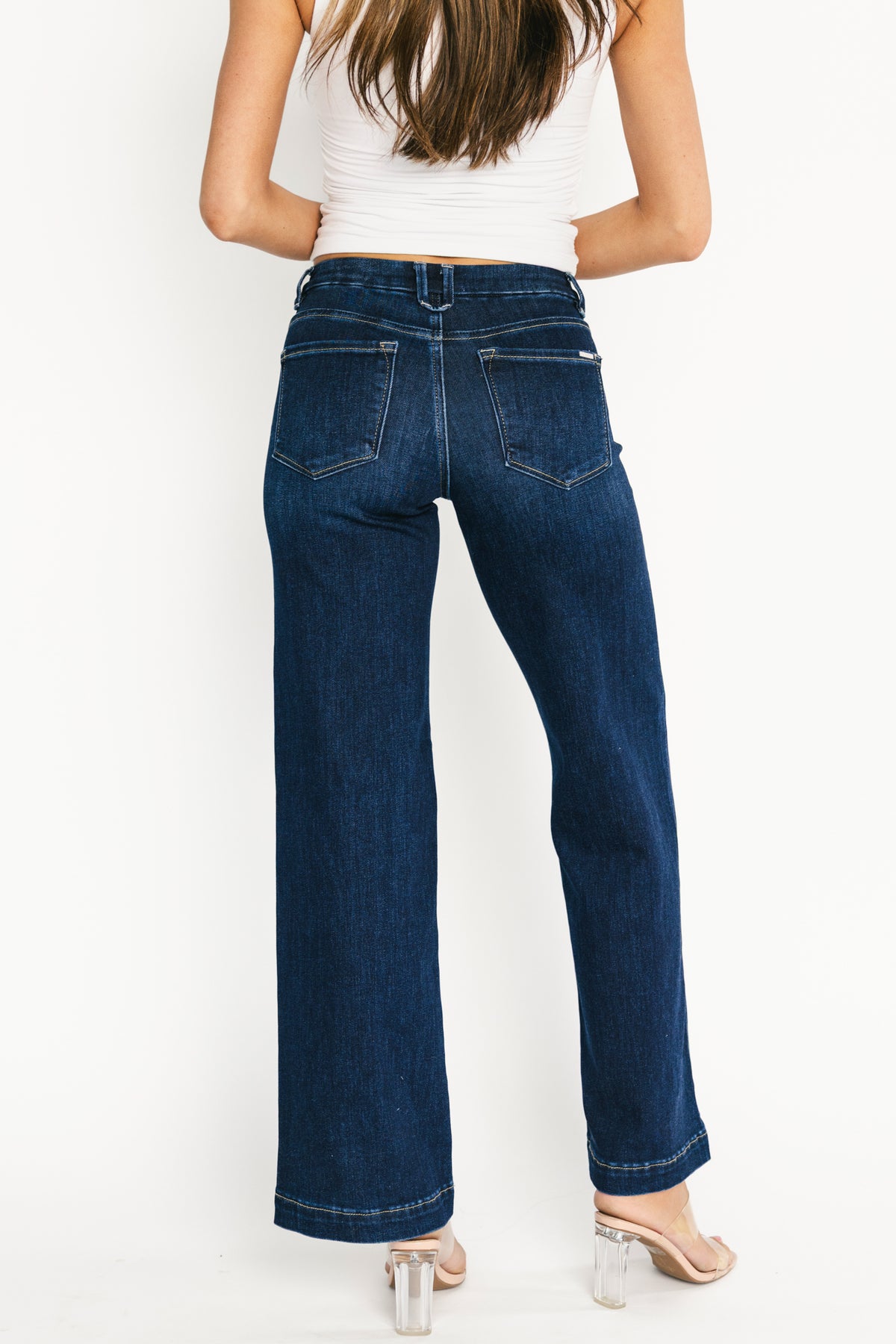 Close-up of waistband and button-and-zip fly on Charme dark wash jeans highlighting fabric texture and topstitching.
