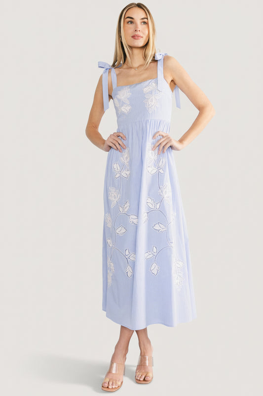Three-quarter view of Enora maxi dress showing embroidered floral detail across the bodice and flowing maxi skirt.