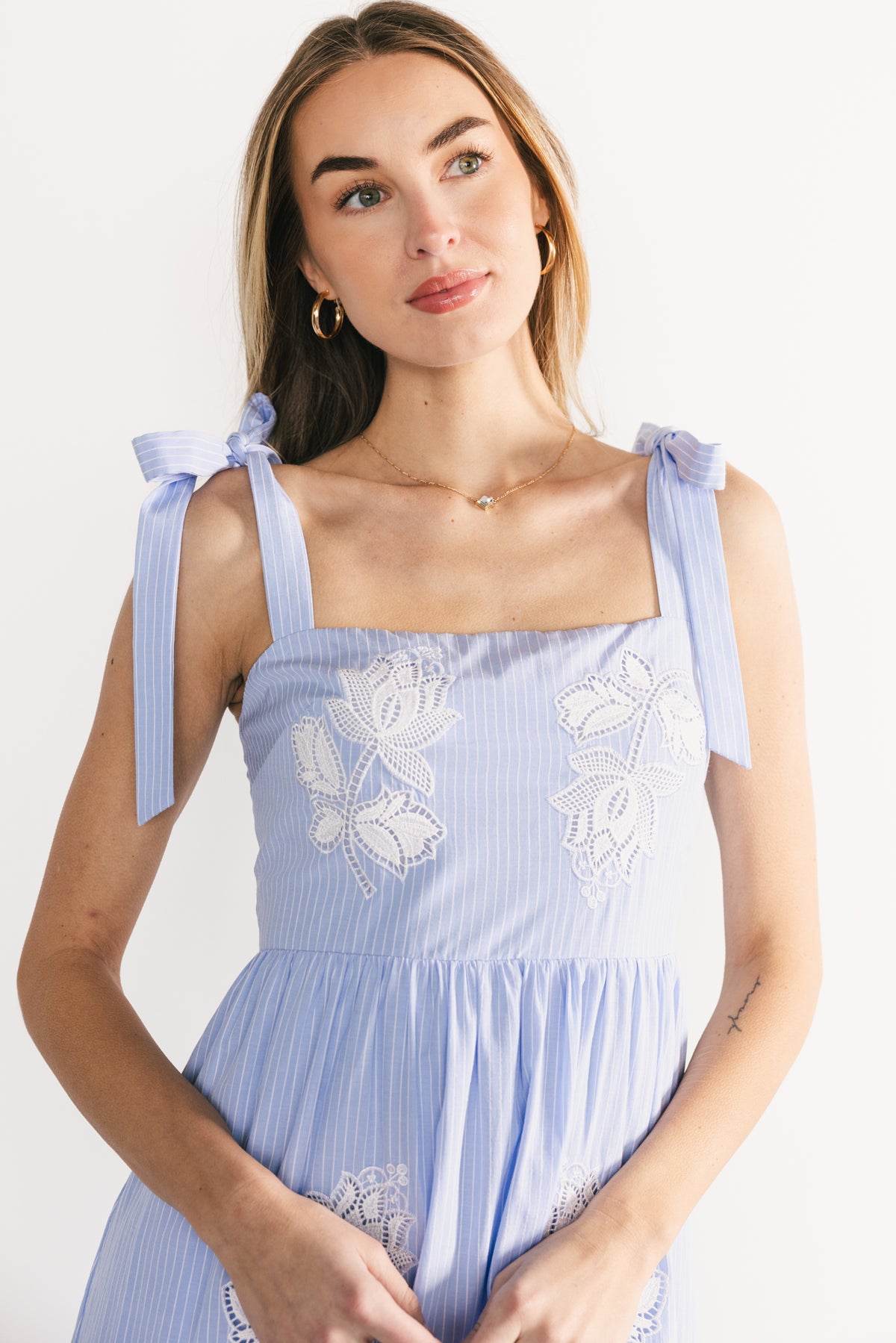 Detail close-up of floral embroidery and blue-and-white stripe fabric texture on the Enora bodice.