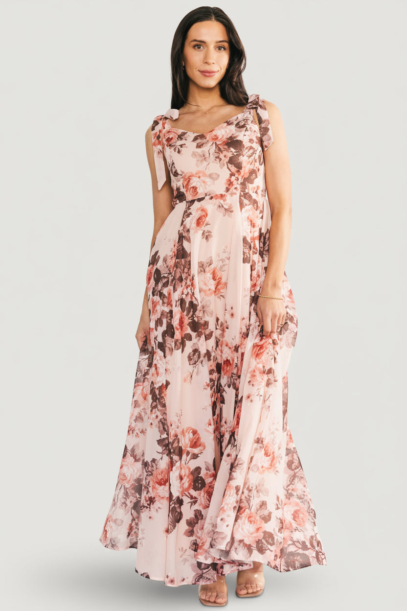 Side view of blush floral chiffon Macey Maxi Dress highlighting adjustable self-tie straps and the dress' graceful drape in motion.