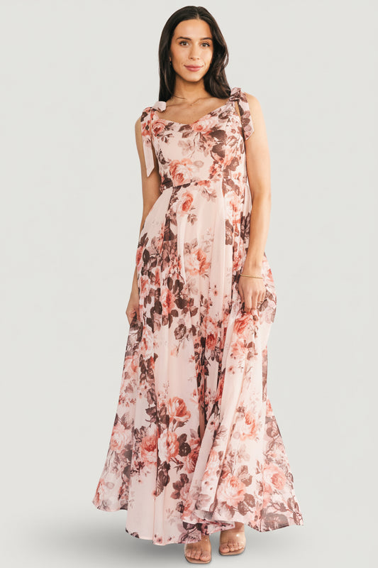 Side view of blush floral chiffon Macey Maxi Dress highlighting adjustable self-tie straps and the dress' graceful drape in motion.