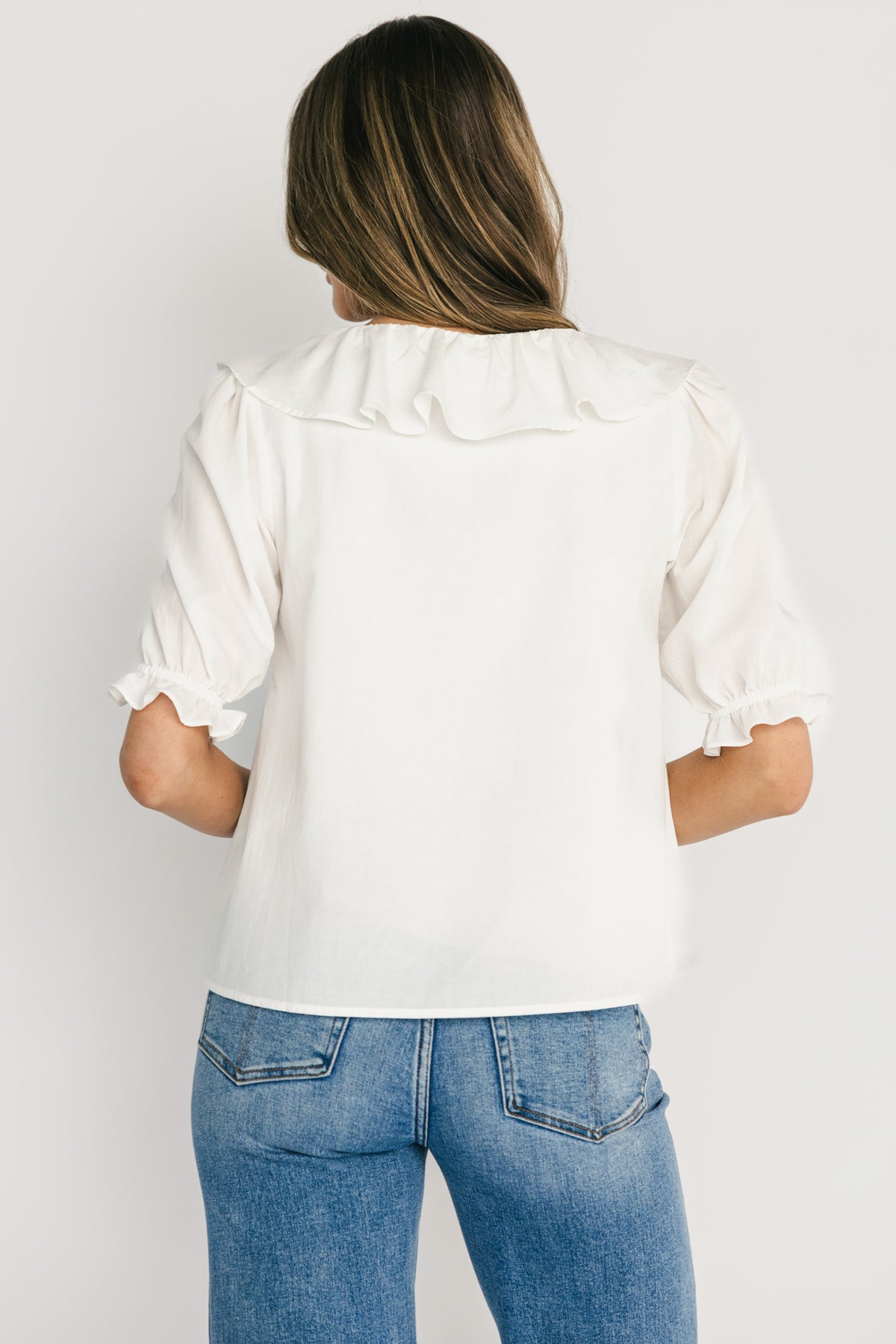 Detail close-up of short sleeve with elastic ruffle cuff on off-white Daisy Ruffle Button-Up Top, showing finish and fabric weave.