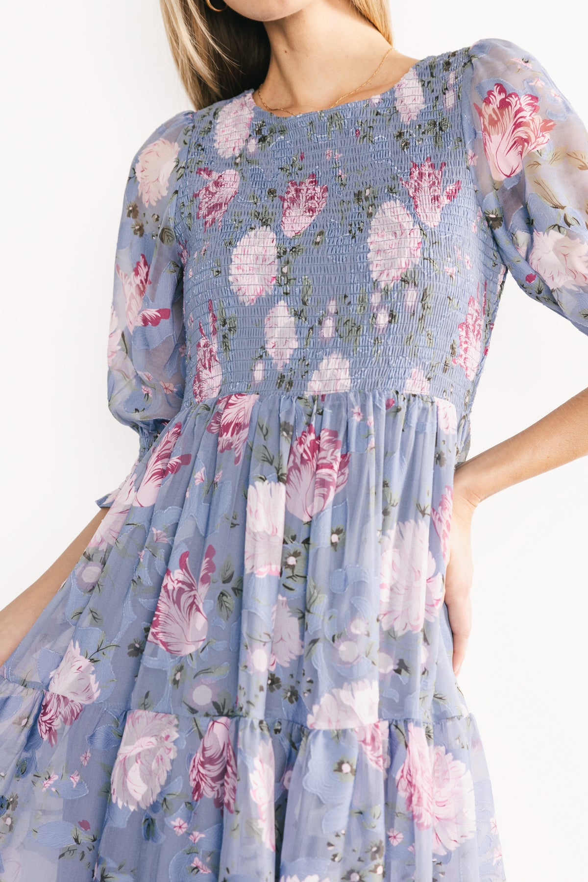 Back view of dusty blue floral midi dress showing seam lines, tiered hem, and full lining for smooth shape and coverage.