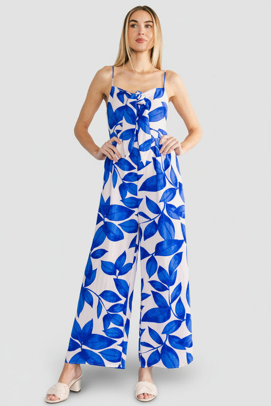 Model wearing Noémie Jumpsuit in cobalt leaf print, angled three-quarter view showing loose straight leg and hidden side pocket detail.