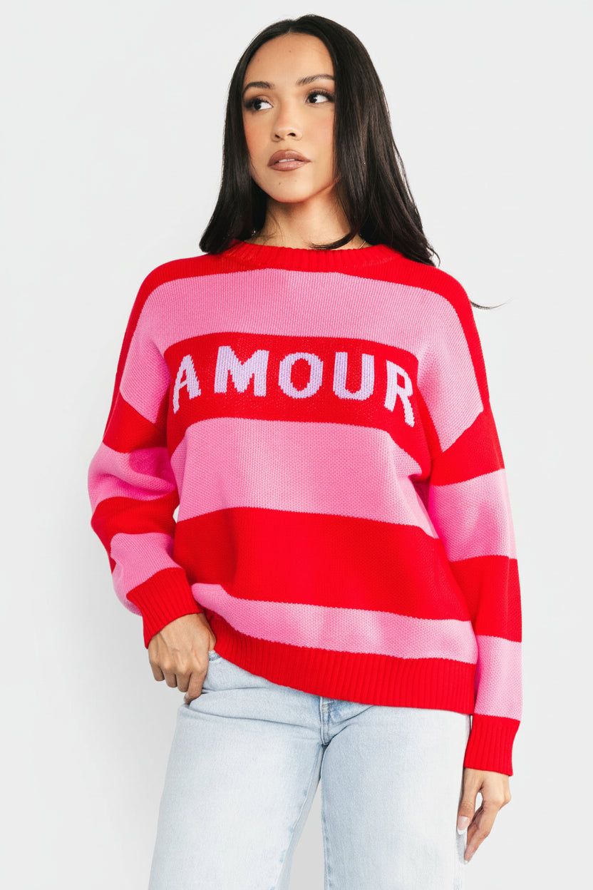 Front view of model wearing Amour Striped Sweater in pink and red stripes, oversized pullover fit with round neckline visible, relaxed drape.