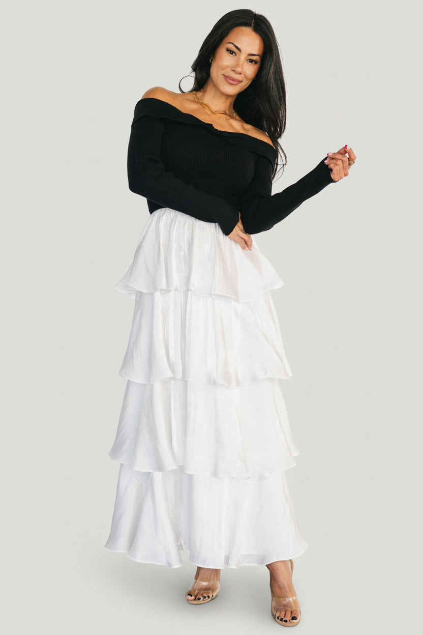 Detail photo of the white satin tiered skirt and hem ruffles, demonstrating volume and refined finish.