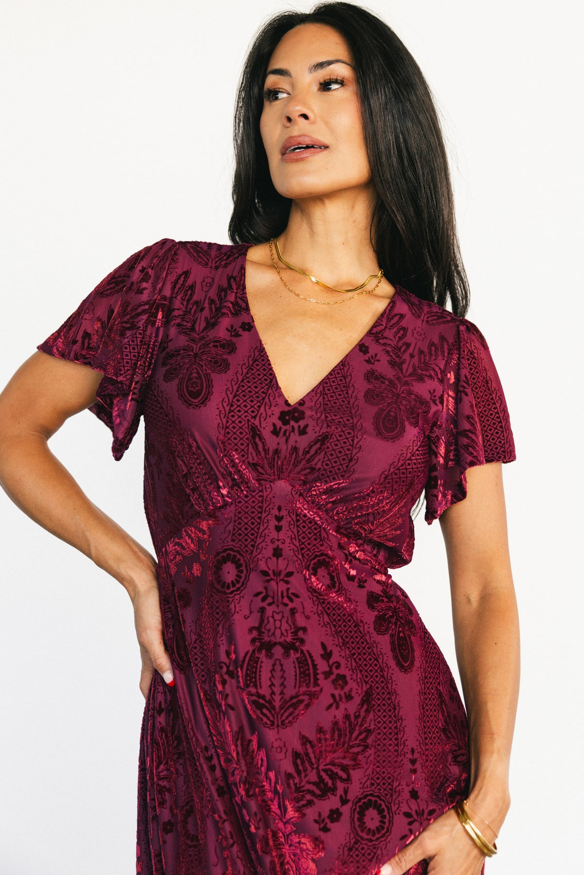 Side view of Kimberly Velvet Maxi Dress in wine showing flutter short sleeves, empire waistline, and textured burnout velvet fabric.