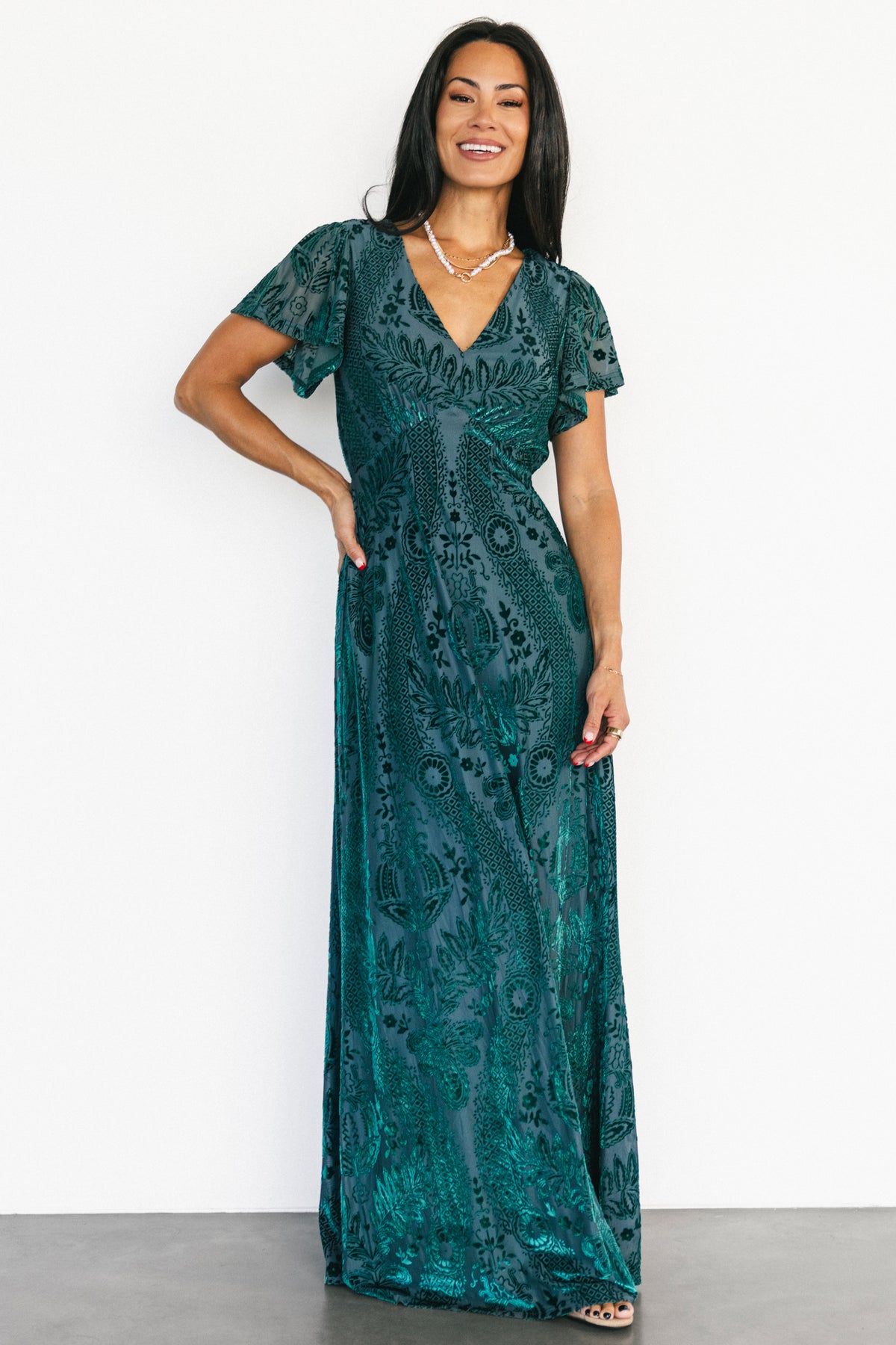 Full-length front view of the Kimberly emerald velvet burnout floral maxi dress, showing the V-neck, empire waist, and flowing skirt details.