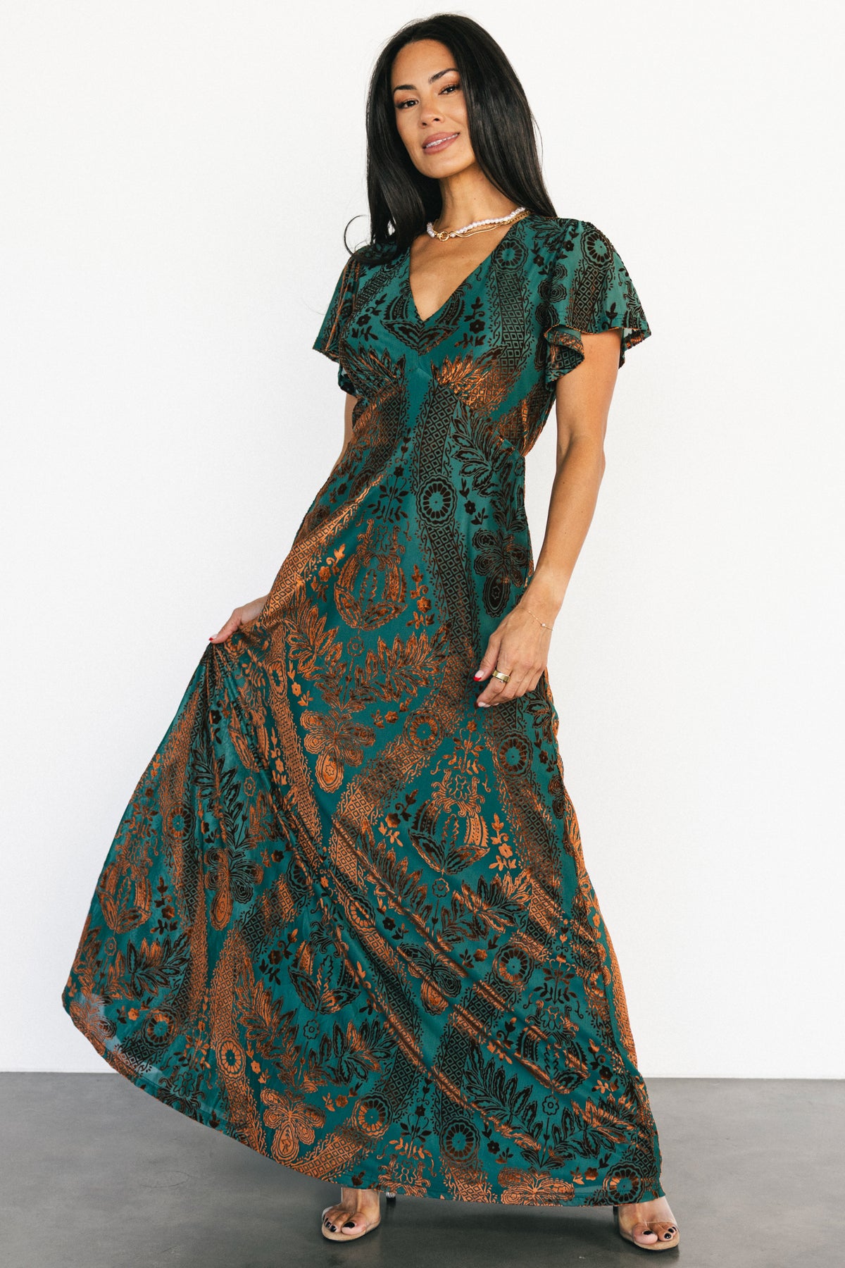 Full-length front view of the Kimberly velvet maxi dress in jade with bronze burnout floral velvet, V-neck and flutter sleeves.