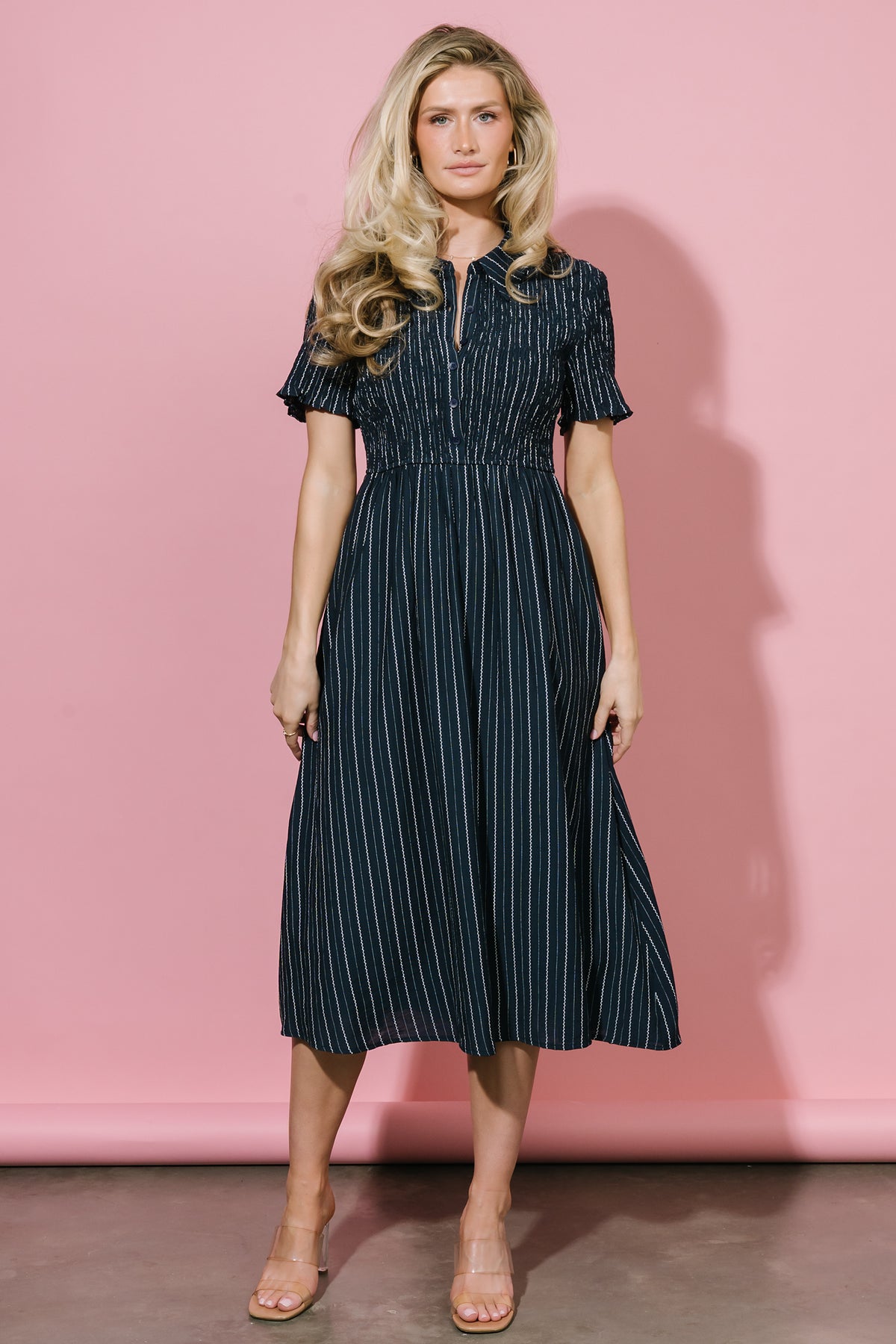 Close-up of smocked bodice and short sleeve detail on Dottie navy dress, showing fabric texture, stitch detail and subtle vertical stripe.