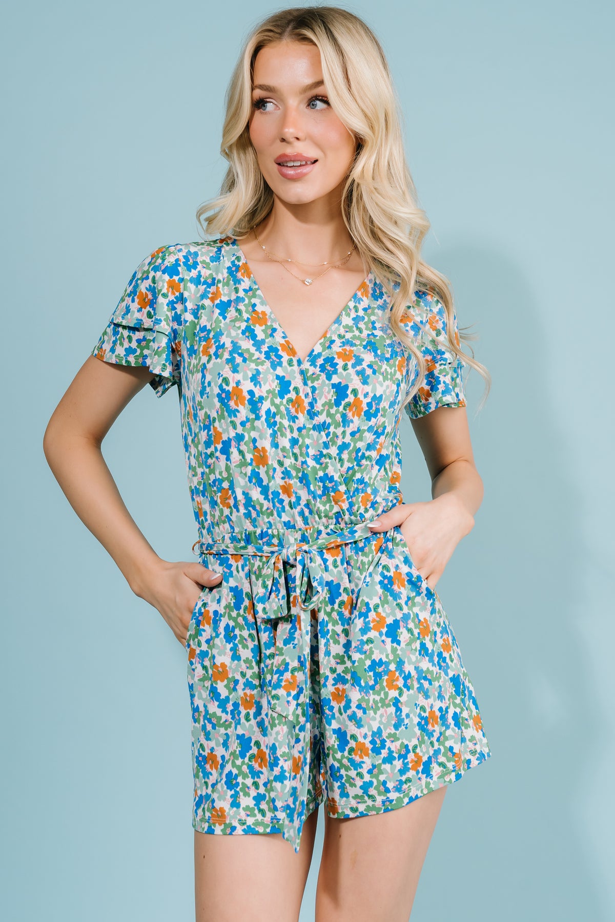 Detail photo of the removable self-tie belt and functional side pocket on the blue and green multi floral romper.